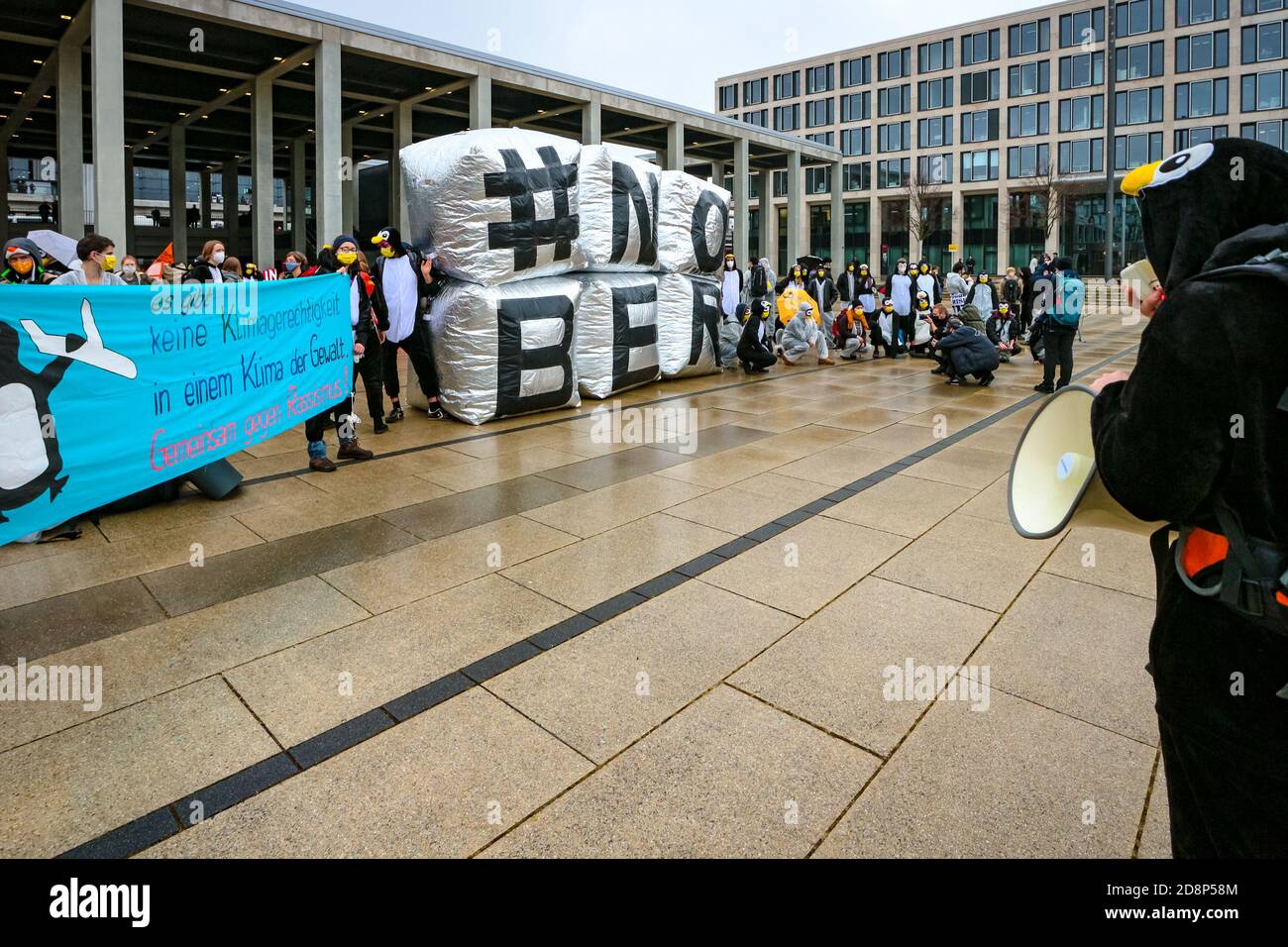 Protestor im Pinguin-Kostüm mit Megaphon am '#NOBER'-Schild als Klimaaktivist protestieren gegen die Eröffnung des Flughafens Berlin Brandenburg (ber). Stockfoto