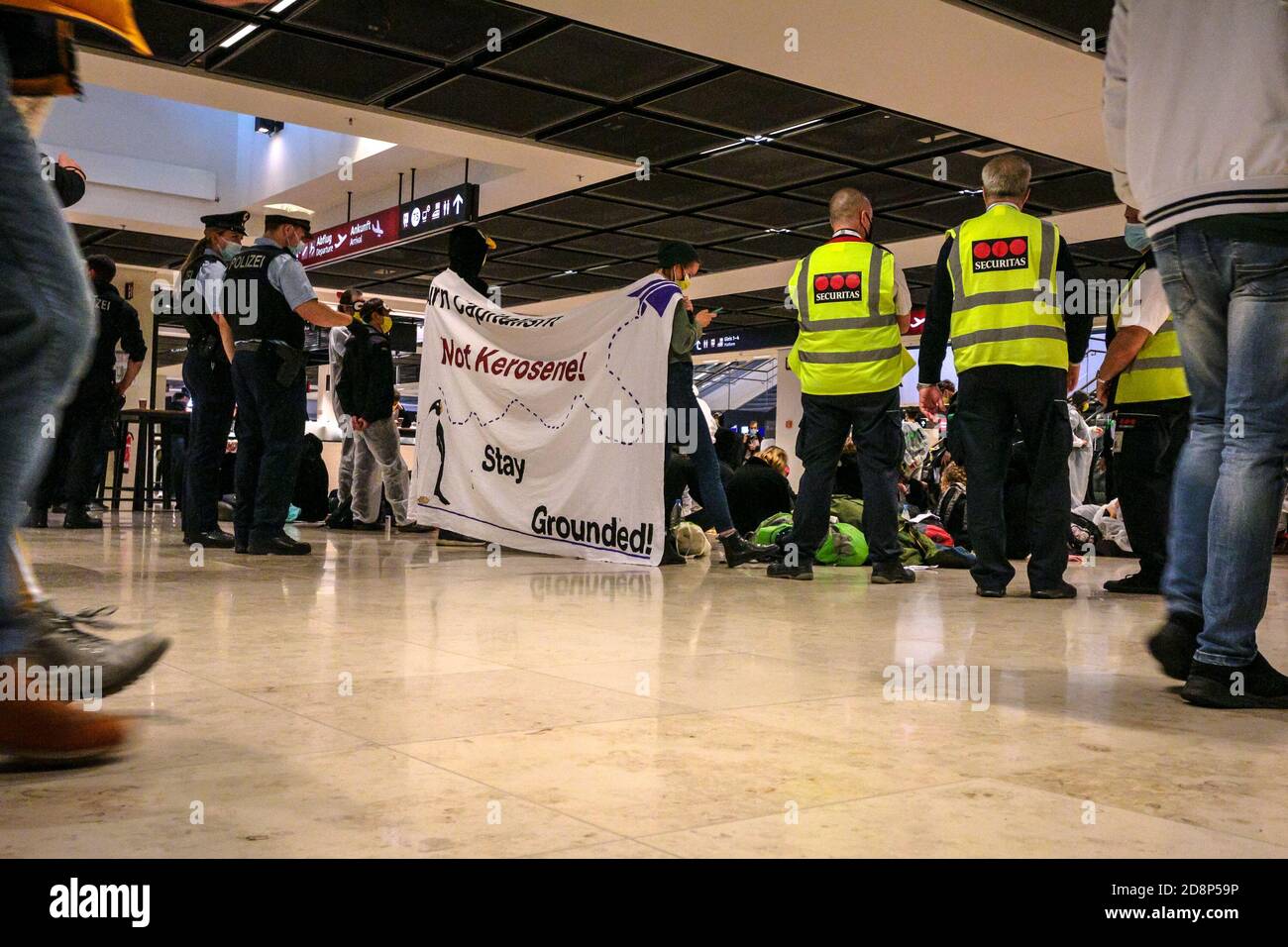 Klimaaktivisten protestieren mit einem "Stay Grounded"-Schild gegen die Eröffnung des neuen Flughafens Berlin Brandenburg International (BER). Stockfoto