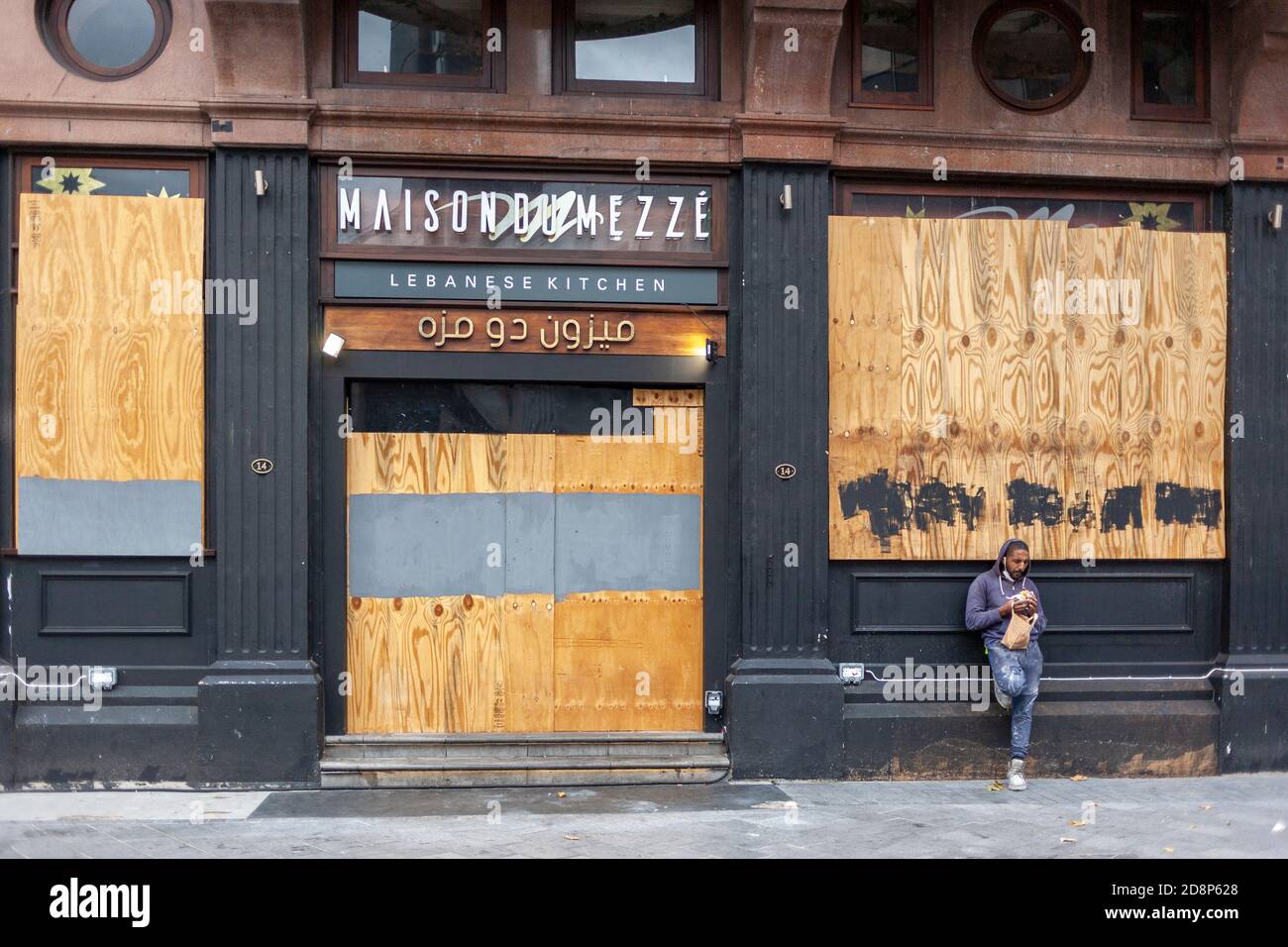 Ein männlicher Arbeiter steht vor einem aufgekiegelten Restaurant, der während der COVID-Pandemie 2020 sein Mittagessen isst. Leicester Square, London, England Großbritannien Stockfoto