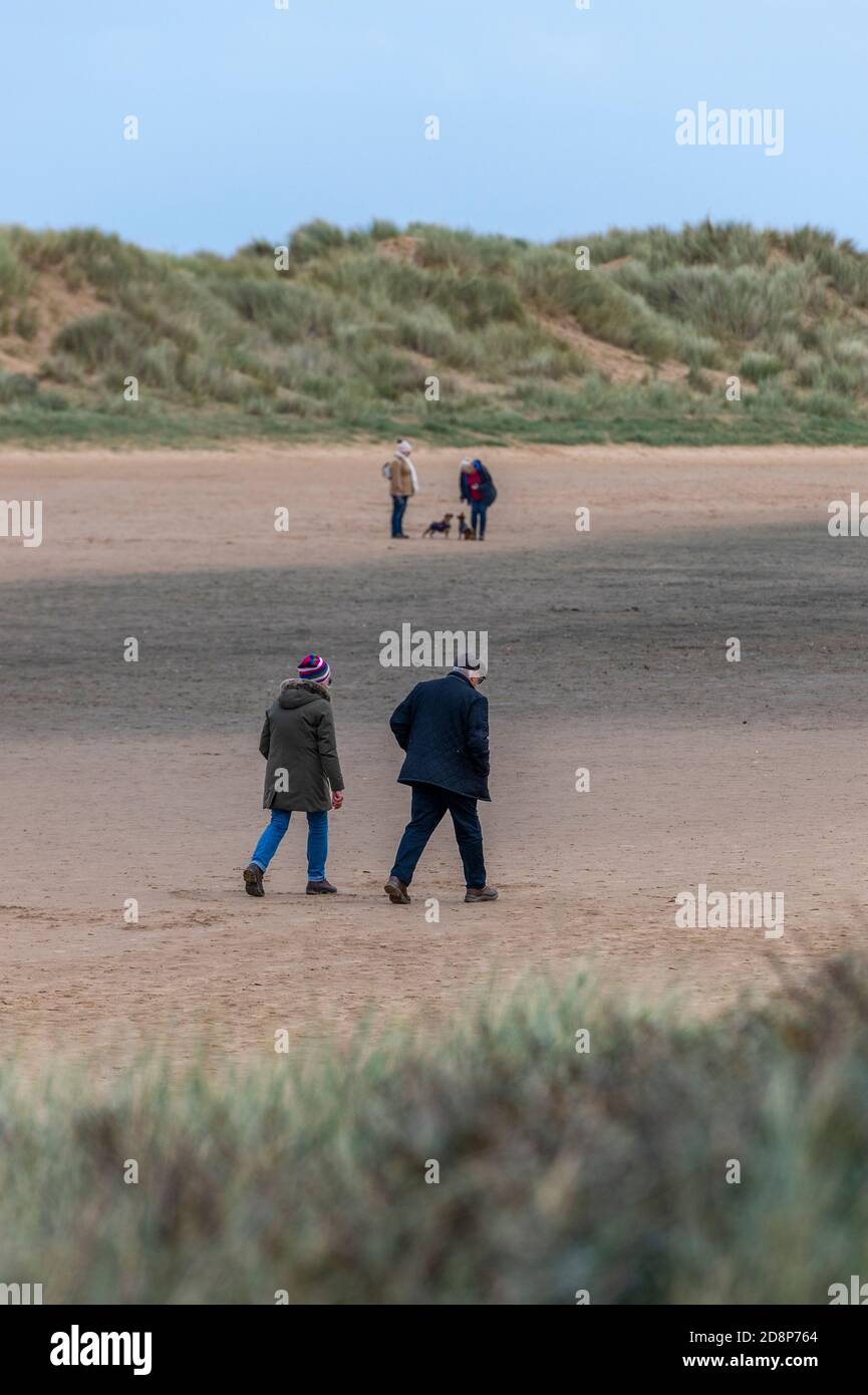 Ältere oder ältere Rentnerpaare, die gemeinsam am Sandstrand am holkham Hall Beach an der norfolk-Küste spazieren Stockfoto