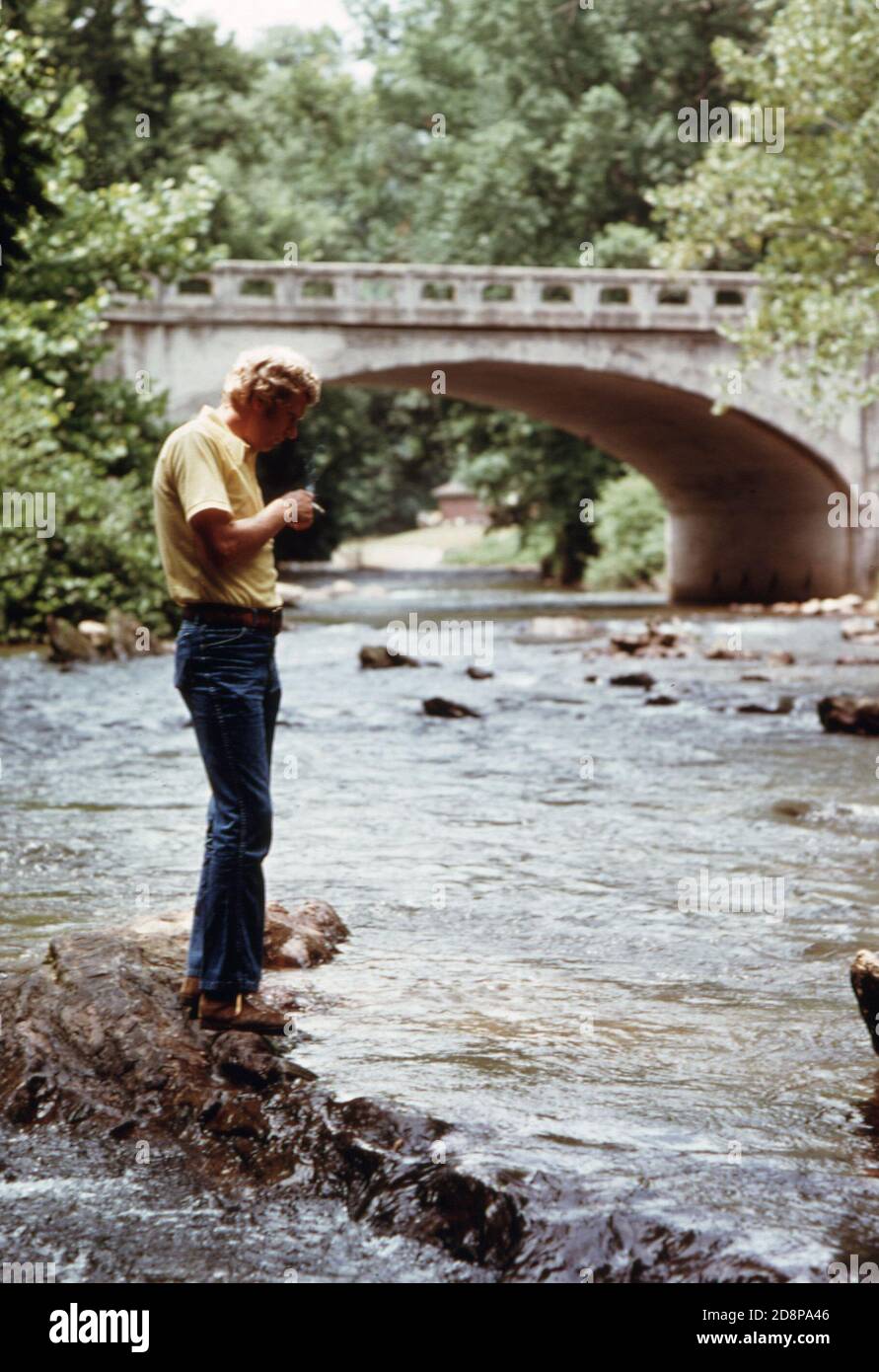 Tourist pausiert für einen Moment der Einsamkeit der Chattahoochee Fluss südlich der Georgia Highway 17/75 Brücke am westlichen Eingang zu Helen; eine kleine Berggemeinde von etwa 270 Menschen. Es war ein typisches Dorf in der Gegend bis 1969, als lokale Beamte Geschäftsleute und Bewohner befürworteten die Renovierung des Geschäftsviertels mit einem bayerischen alpinen Thema. Der Erfolg des Projekts zog neue Unternehmen und einen Anstieg der Touristen zwischen Mai und Oktober. Stockfoto