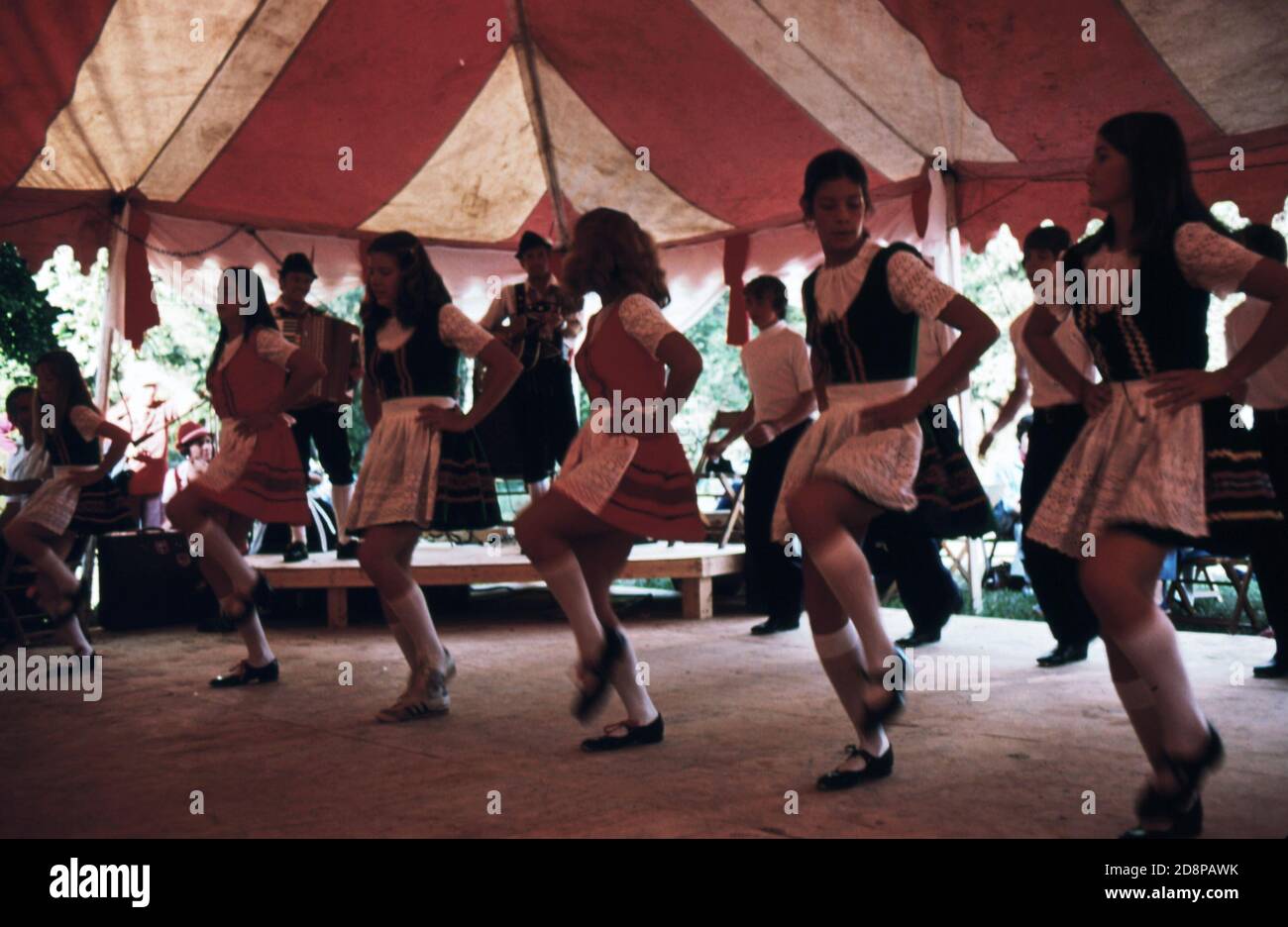 'Eine Gruppe von ''unicoi Cloggers'' aus White County; Georgia führen amerikanische Bergtanz-Routinen zu bayerischer Polka-Musik während des fünften jährlichen Oktoberfestes in Helen. Die Mädchen führen einen Verstopfungsschritt aus, der als "Hüpfhüpfen" bekannt ist. Das jährliche Festival ist ein Ergebnis der Transformation des Geschäftsviertels der kleinen Gemeinde mit einem einheitlichen alpinen Thema. Der Erfolg des Projekts hat zu mehr Geschäft und einem Anstieg des Tourismus geführt." Stockfoto