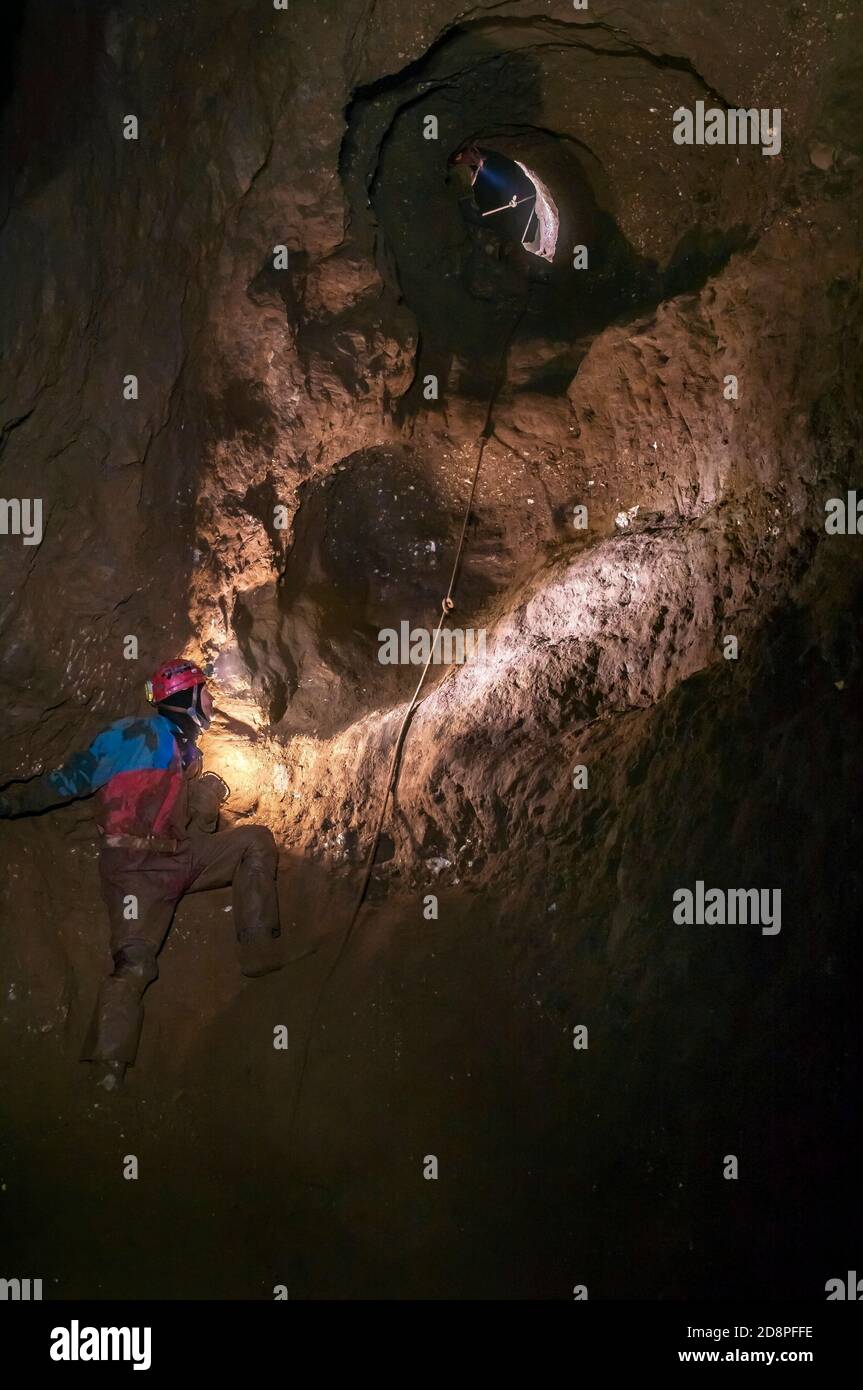 Große Höhle mit natürlichen Aderhöhlen, halb gefüllt mit trockenem Sediment, stabilisiert mit Bergarbeiter-Pickwork in Speedwell Cavern in Castleton, Derbyshire. Stockfoto