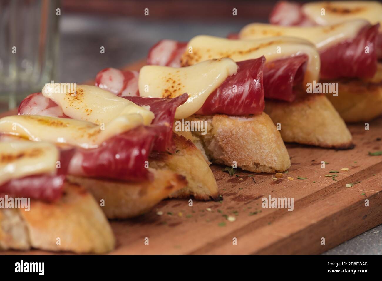 Tapas mit Iberico-Schinken, Mozzarella-Käse, geröstete Paprika auf einer Scheibe geröstetem Baguette mit Olivenöl, Petersilie und Knoblauch Stockfoto