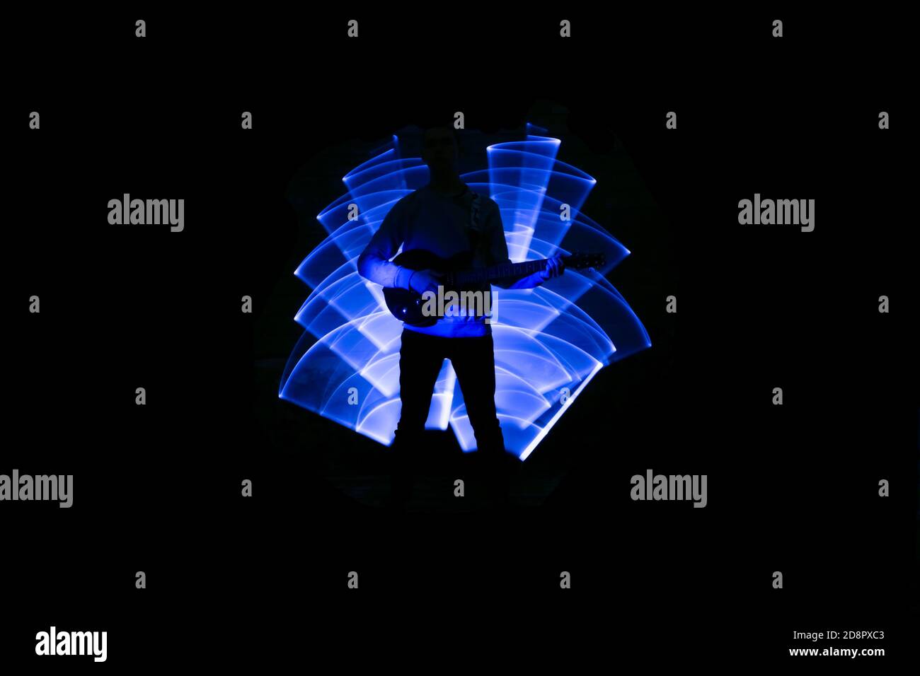 Silhouette eines Mannes mit Gitarre. Lichtszene mit Musikinstrument und Lichteffekten im Hintergrund. Stockfoto