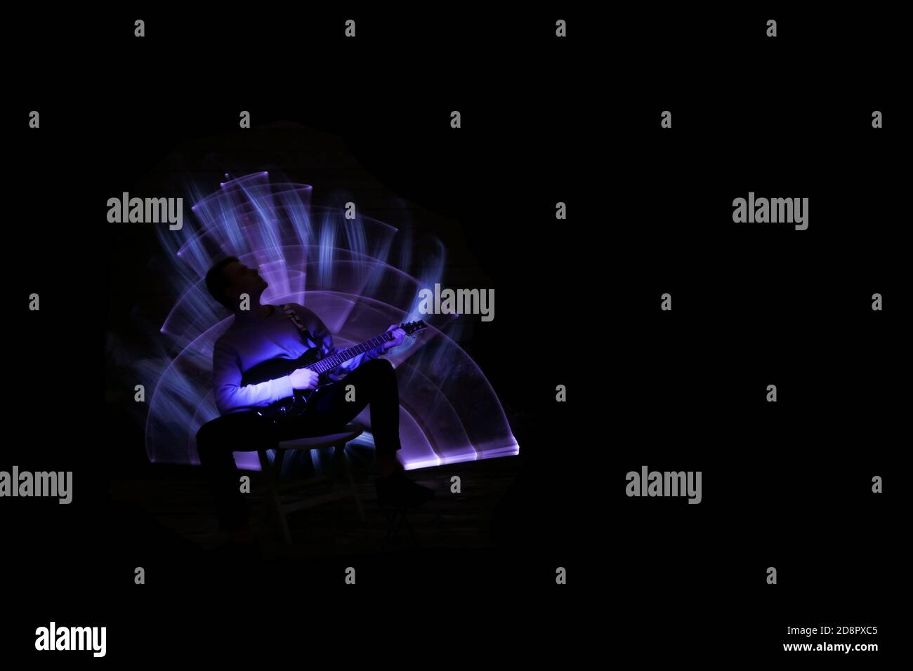 Silhouette eines Mannes mit Gitarre. Lichtszene mit Musikinstrument und Lichteffekten im Hintergrund. Stockfoto