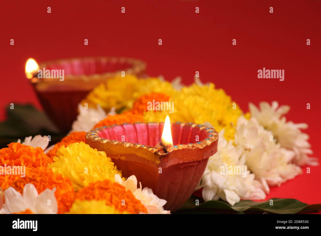 Blume Rangoli für Diwali oder Pongal Festival gemacht mit Marigold oder Zendu Blumen und Clay Öllampe über rotem Hintergrund. Kopierraum. Licht auf der linken Seite Stockfoto