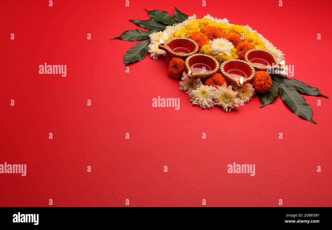 Blume Rangoli für Diwali oder Pongal Festival gemacht mit Marigold oder Zendu Blumen und Clay Öllampe über rotem Hintergrund. Kopierraum. Licht auf der linken Seite Stockfoto