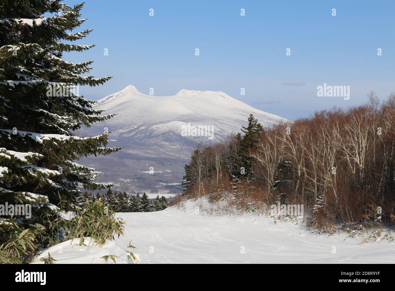 Eine leere Skipiste mit Vulkan in der Ferne Stockfoto