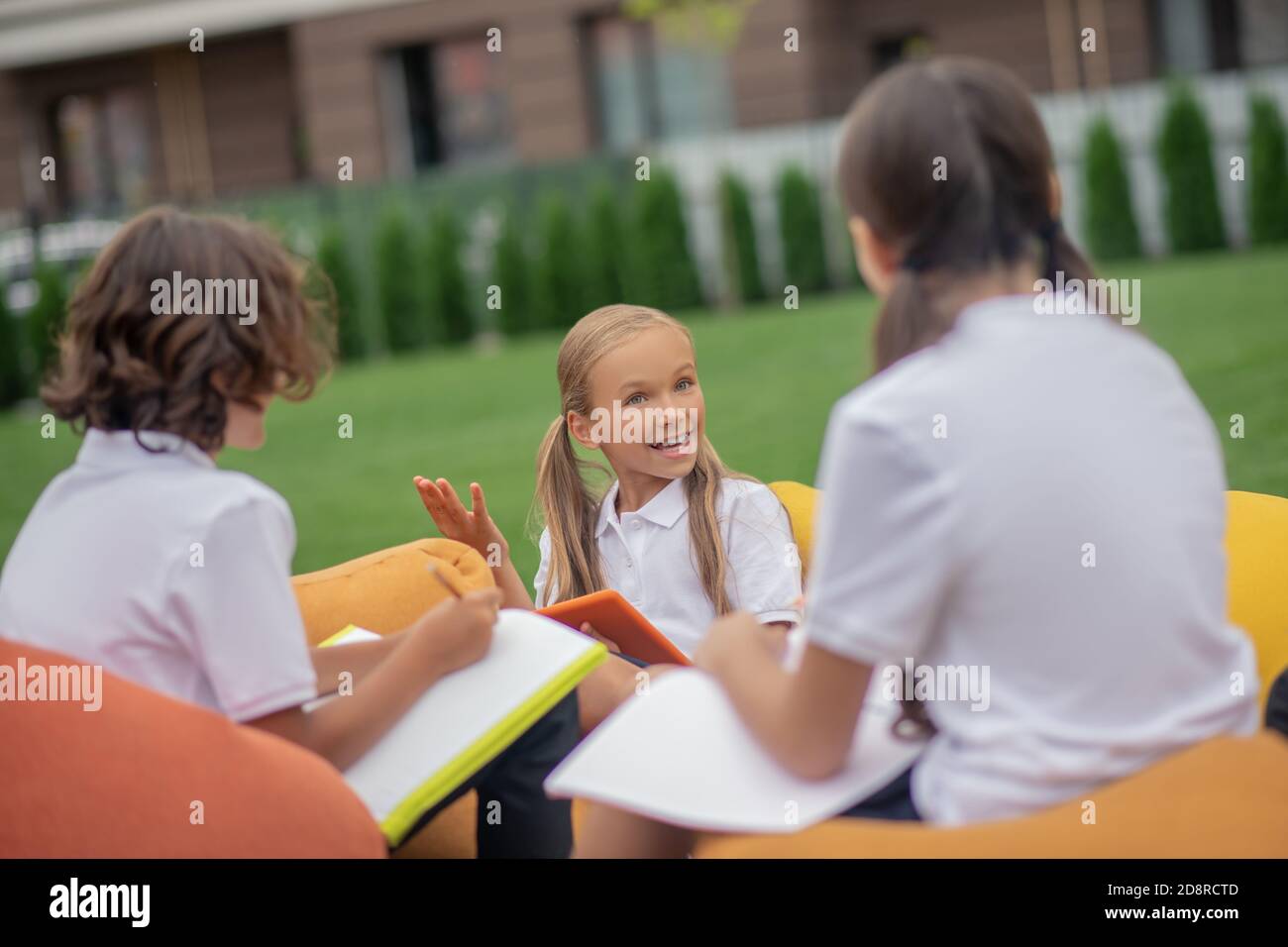 Kinder in weißen Hemden studieren zusammen und schauen positiv Stockfoto