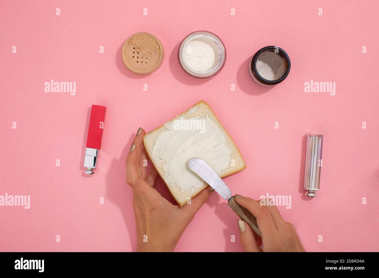 Hände schmieren kosmetische Creme auf Brot Stockfoto