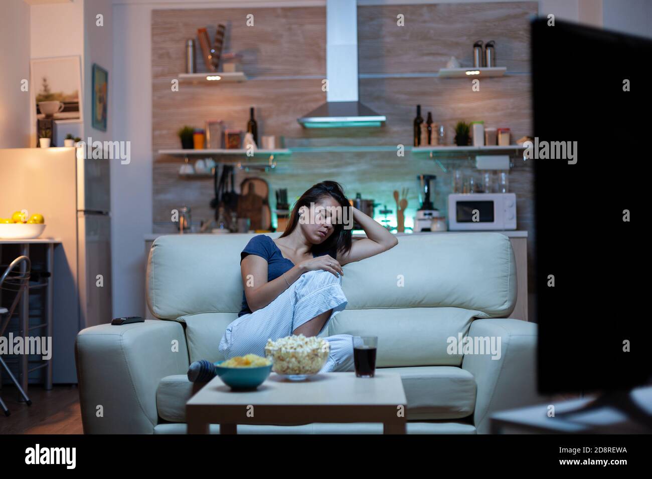 Müde Hausfrau Einschlafen vor dem Fernseher sitzen auf gemütliche Couch im  Wohnzimmer. Erschöpft einsam schläfrig gelangweilte Frau in Schlafanzug  schlafen auf dem Sofa, während Fernsehen nach Hause allein spät in der Nacht