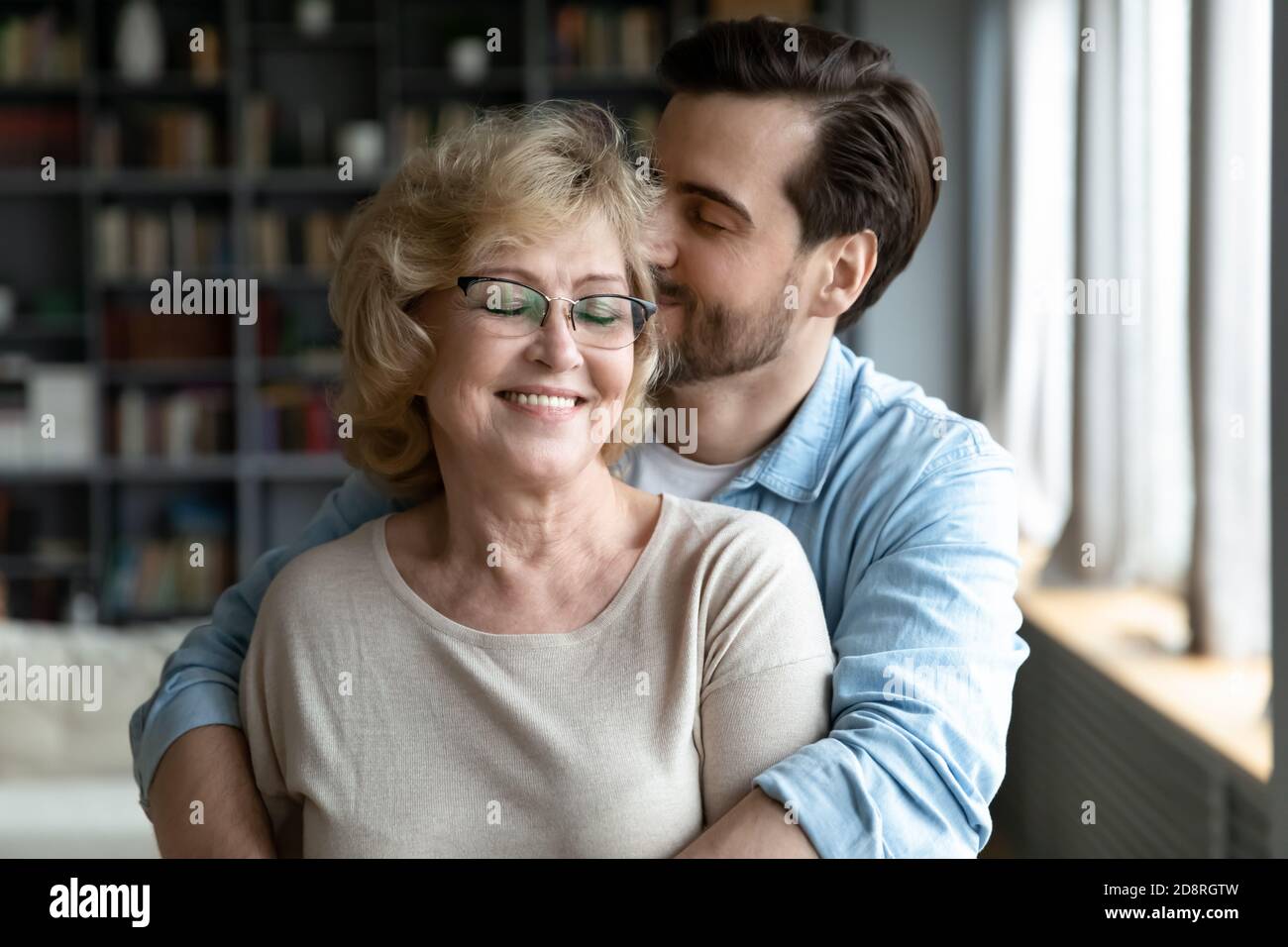 Hingebungsvoller junger Mann, der sich um lächelnde, pensionierte Mutter kümmert. Stockfoto