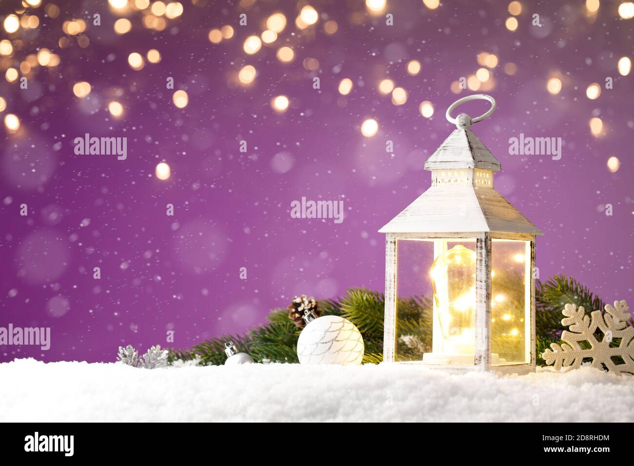Magische Laterne mit weihnachtsspielzeug auf Schnee gegen Lila Hintergrund Stockfoto