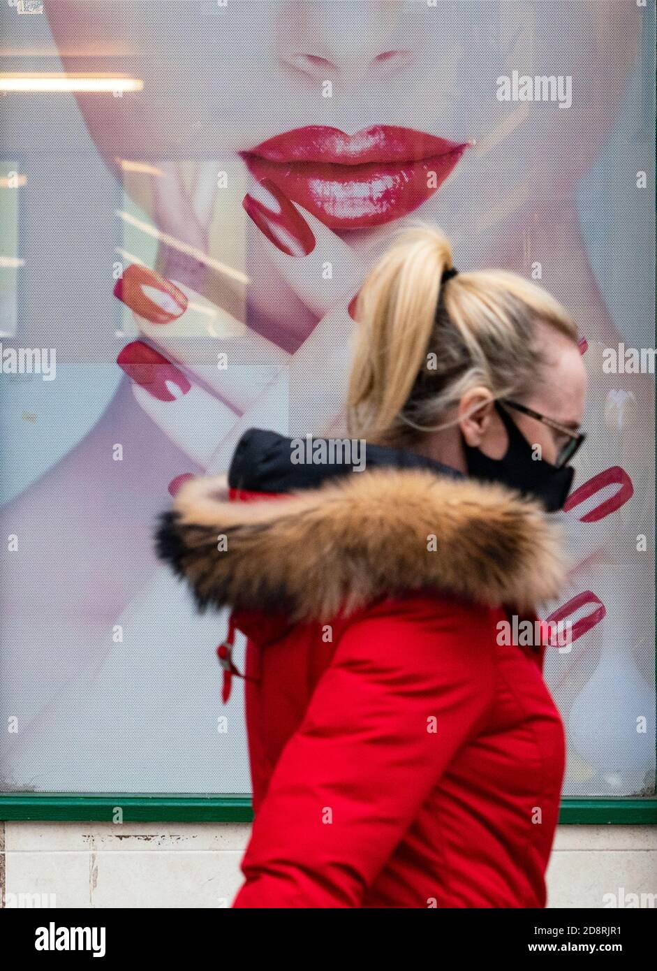 Frau mit Gesichtsmaske geht während der Coronavirus-Pandemie in Schottland, Großbritannien, am Schaufenster der Nagelbar im Stadtzentrum von Airdrie vorbei Stockfoto