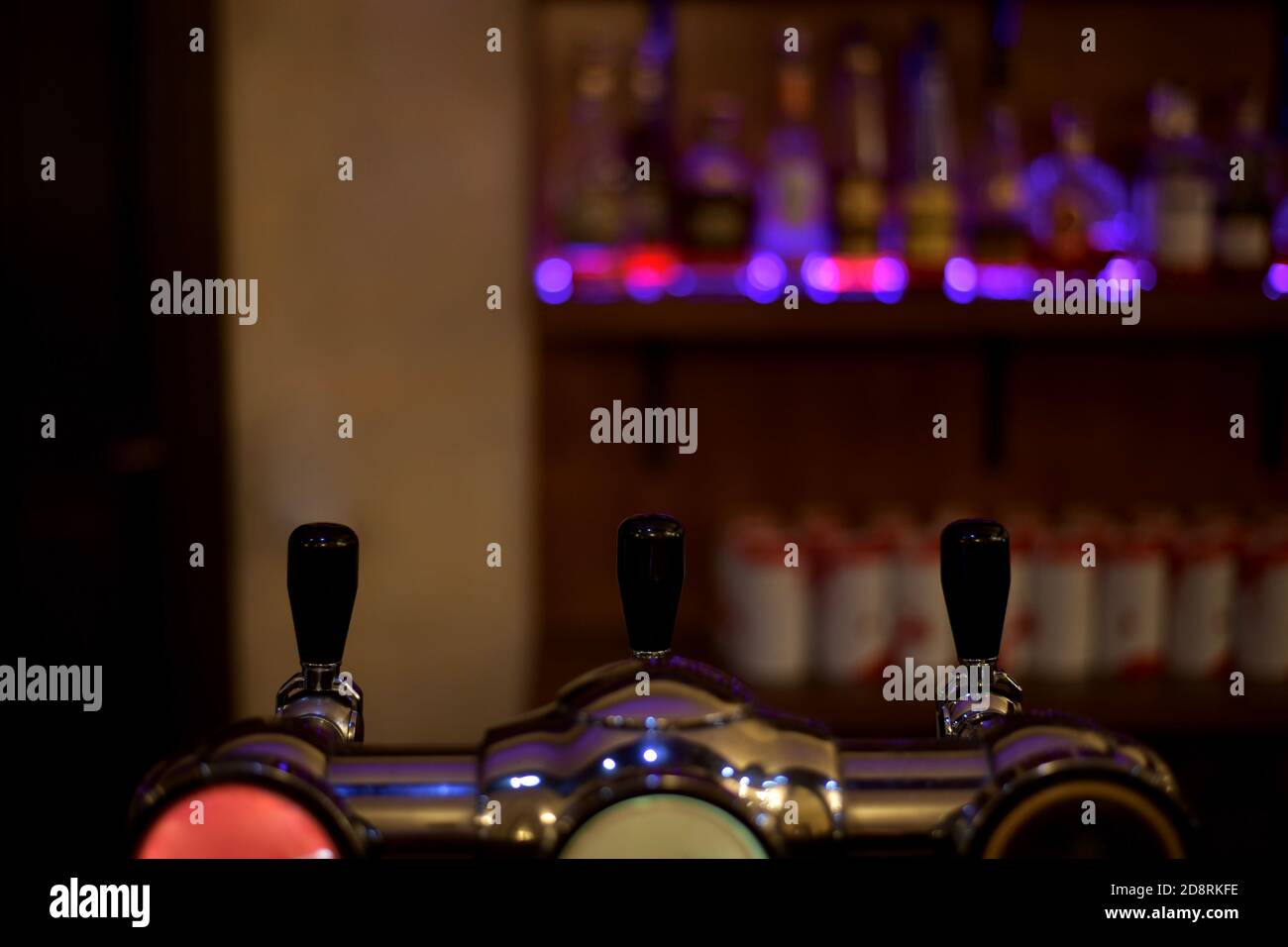 Die Griffe der Abfüllanlage in der Bar, vor dem Hintergrund der Vitrine mit Flaschen in der Beleuchtung. Stockfoto