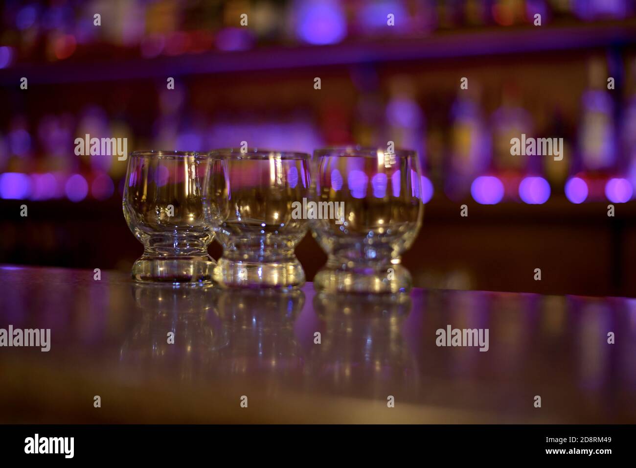Drei kleine Glas Tassen, an der Bar im Licht der lila Lichter Schaufenster. Stockfoto