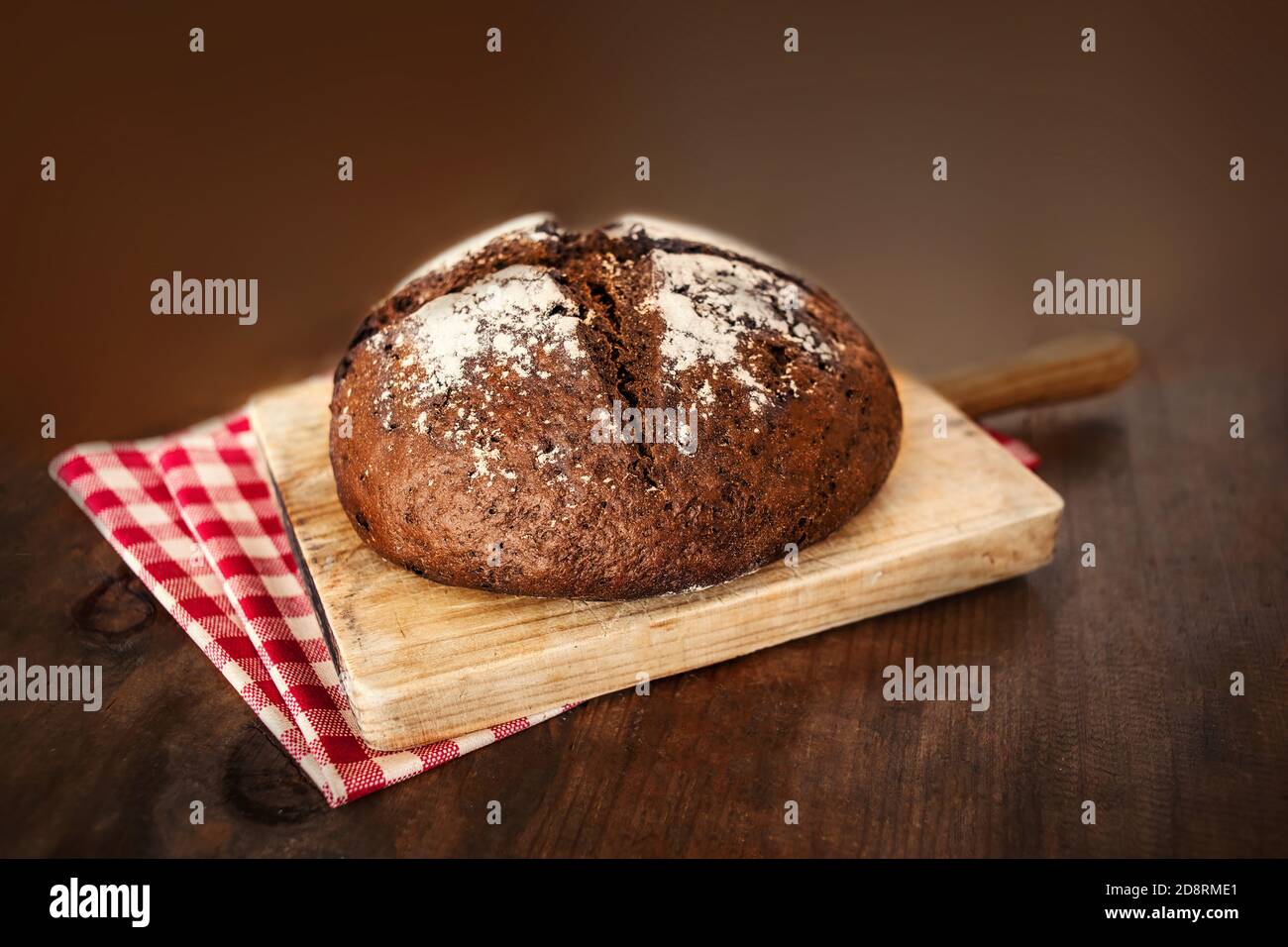 Vollkornbrot auf dunklem ruktischen Holzhintergrund Nahaufnahme. Runder Brotlaib Stockfoto