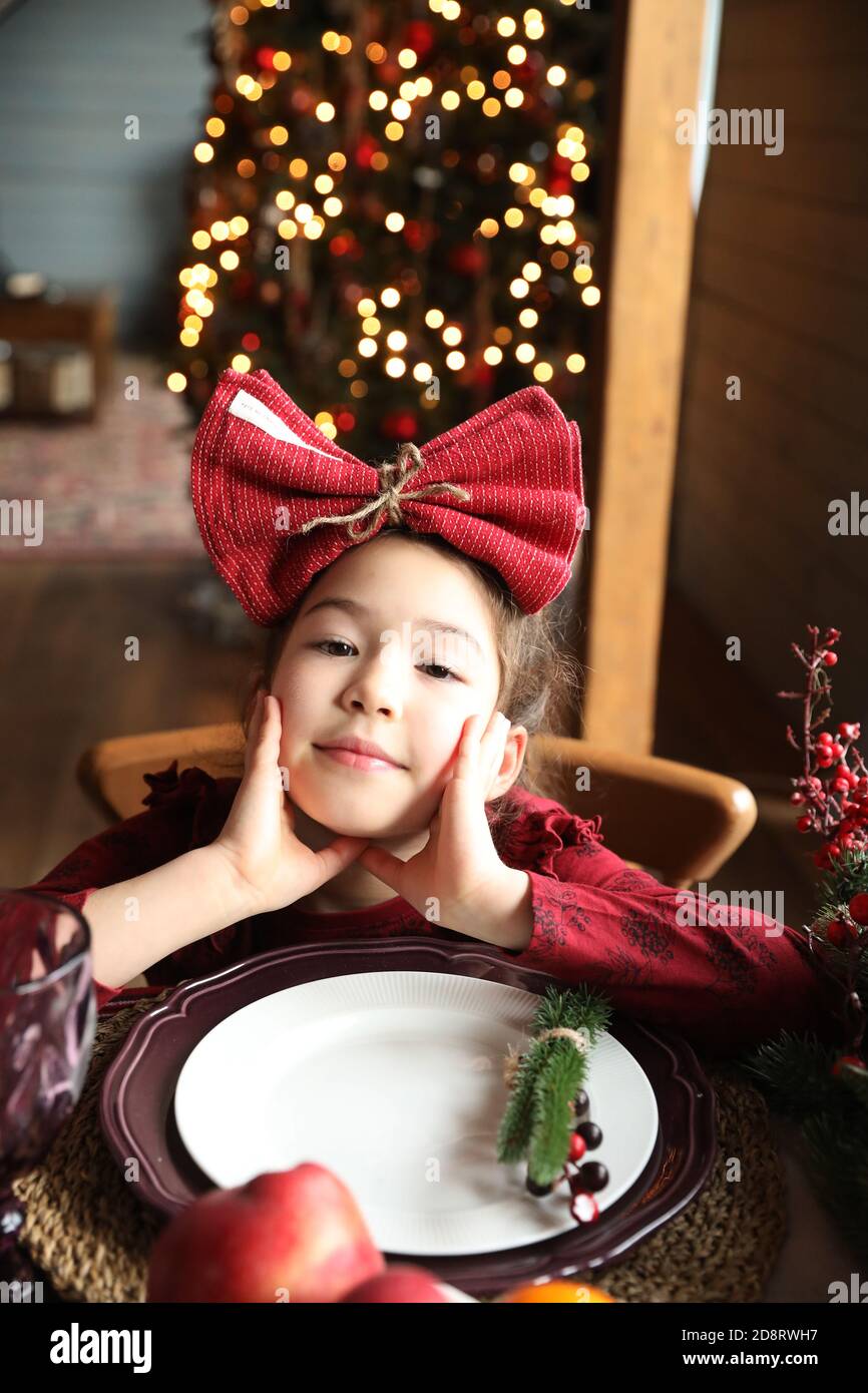 Ein kleines Mädchen wartet auf Weihnachten an einem leeren Teller am Tisch. Stockfoto