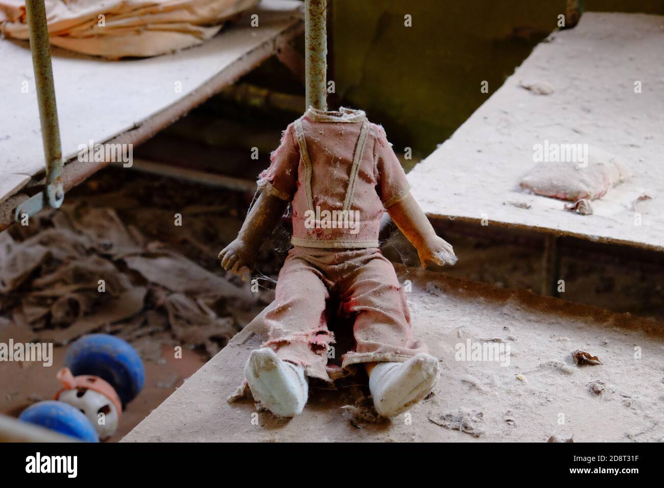 Kinderpuppe ohne Kopf. Ein schmutziges, zerbrochenes Kinderspielzeug aus einem strahlenverseuchten Kindergarten in Tschernobyl. Stockfoto