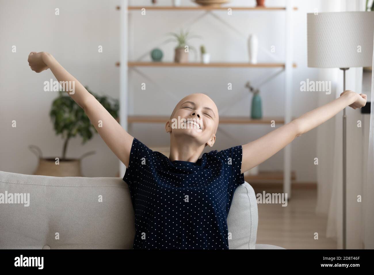 Nahaufnahme lächelnde haarlose Frau streckt die Hände auf der gemütlichen Couch Stockfoto