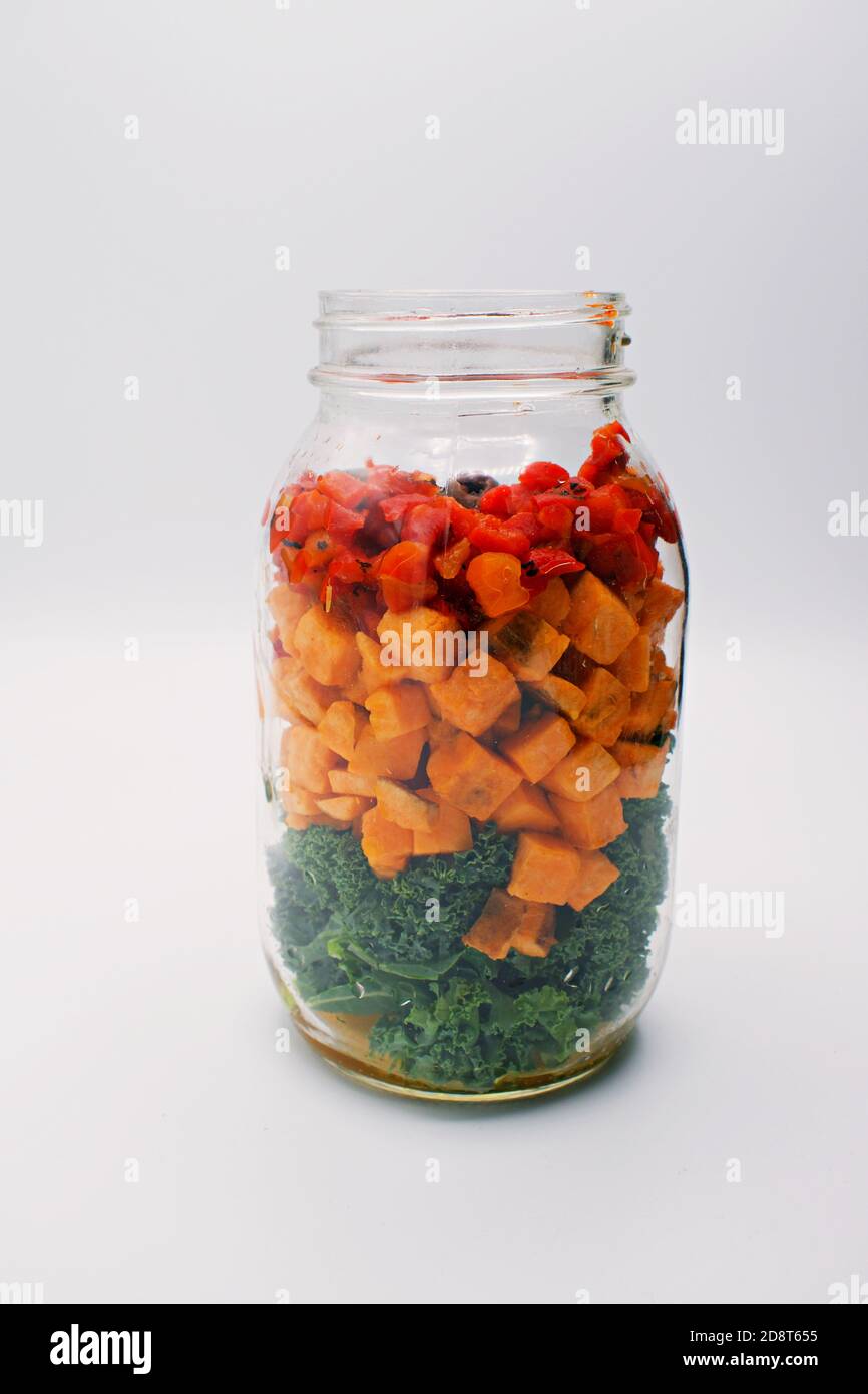 Mason Glas Jar gefüllt mit einer gesunden vegetarischen Mahlzeit: grünkohl, Süßkartoffeln und rote Paprika. Stockfoto