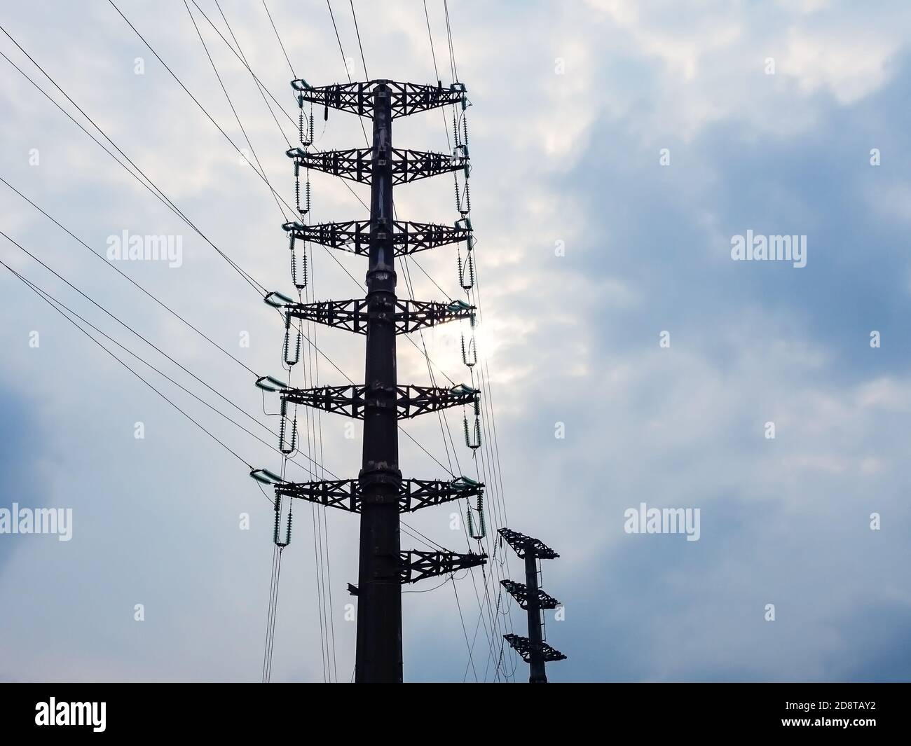 Metallmast mit vielen elektrischen Drähten vor einem wolkigen Himmel Hintergrund. Kraftwerk Stockfoto