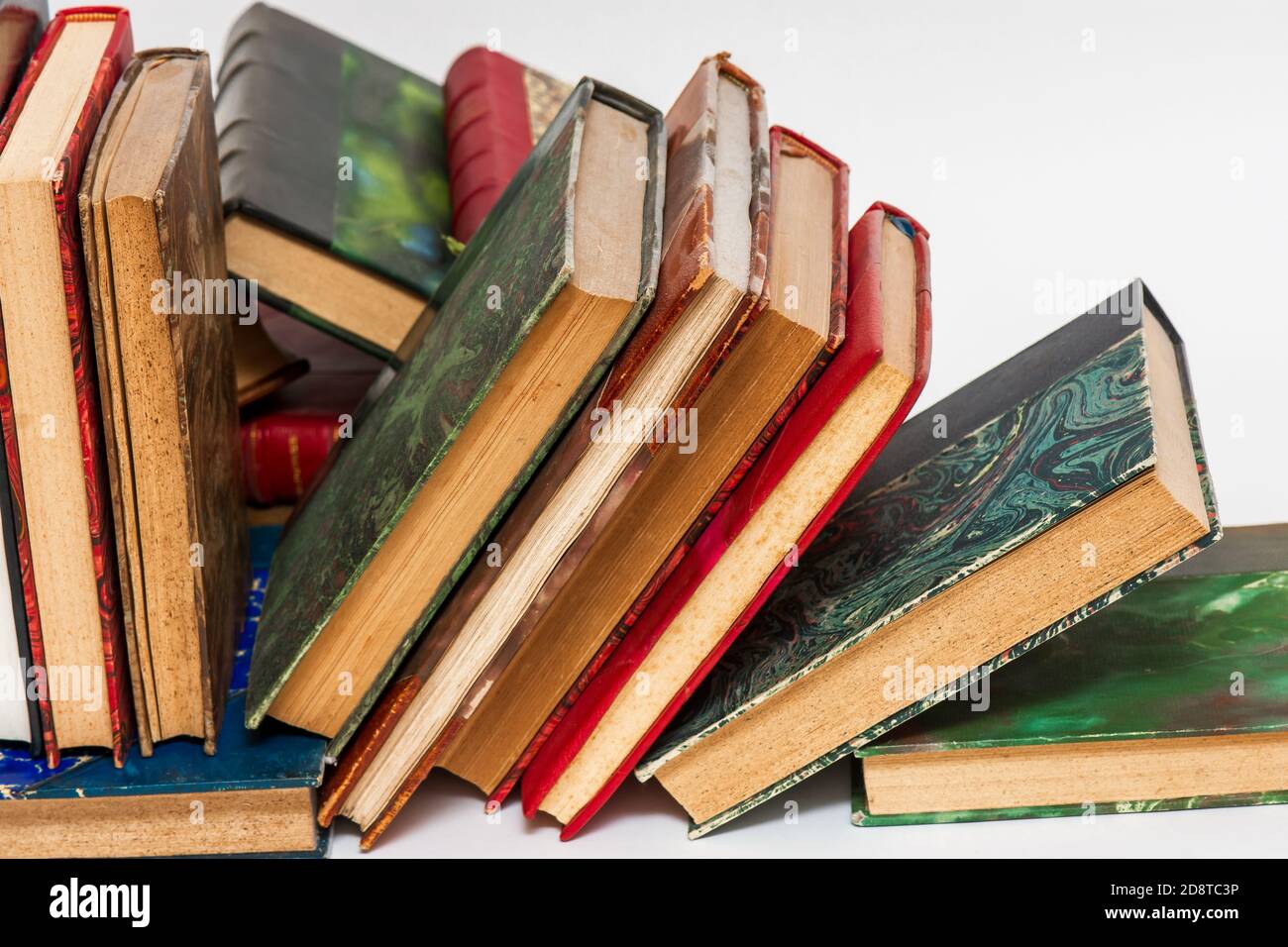 Eingestürzte Reihe von alten Büchern mit alten Einbänden auf einem Weißer Hintergrund Stockfoto