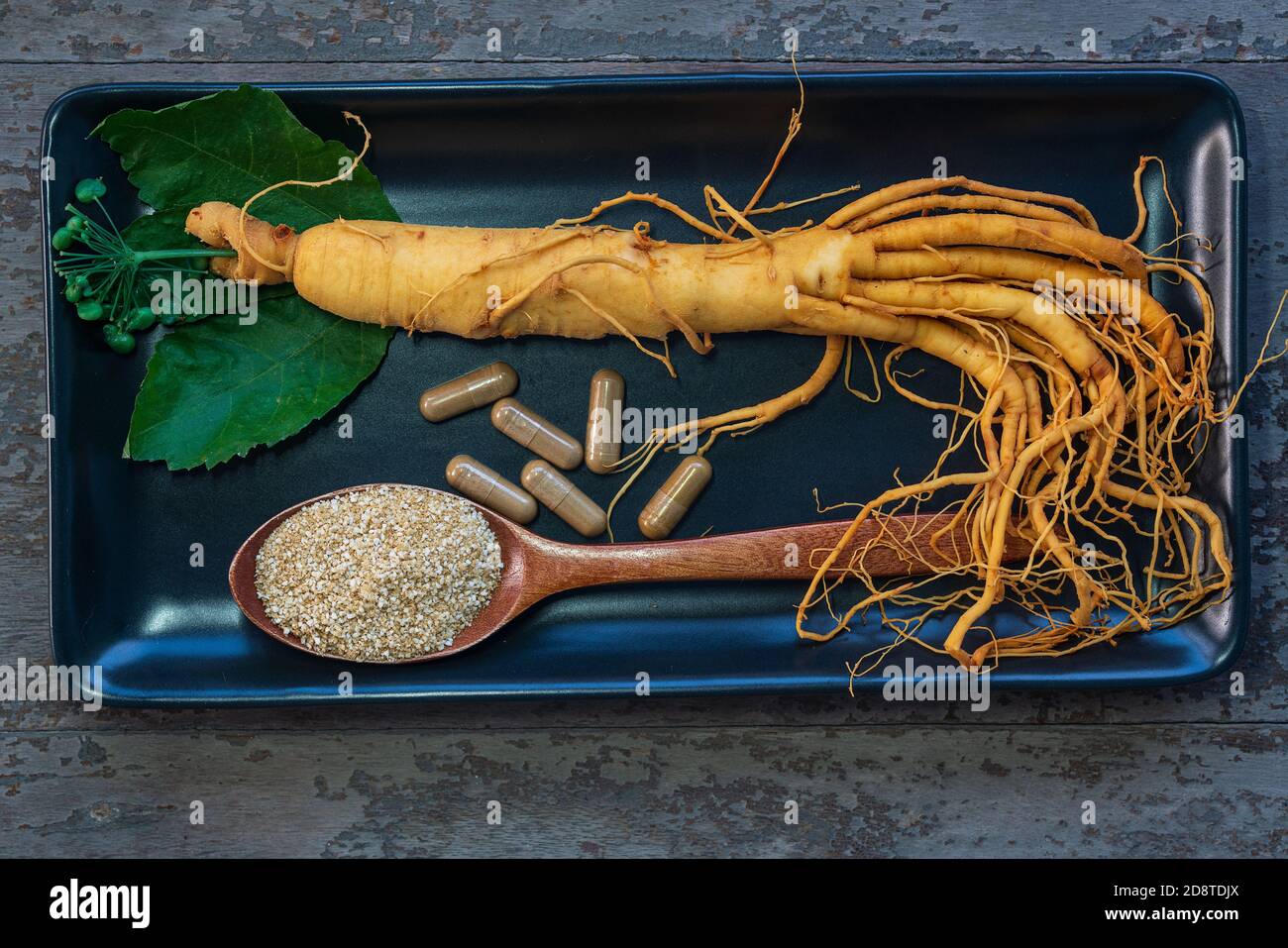 Frische Ginseng Wurzel auf schwarzem Teller mit Pulver für Kapseln Medizin Stockfoto