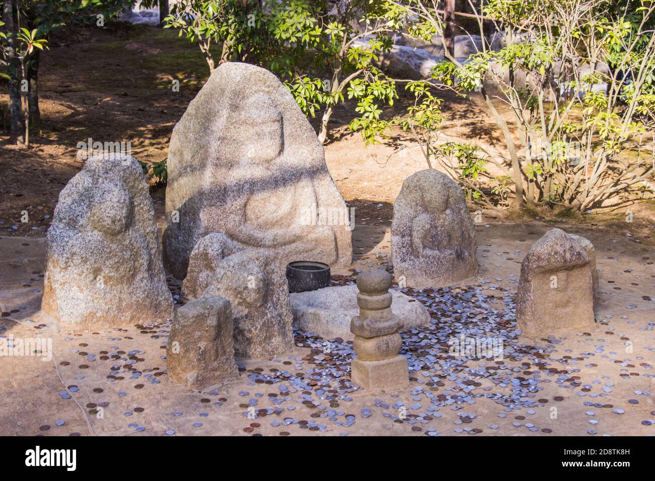 Bereich an Touristen werfen Münzen für Segen beten von Stein buddha an Schnitzereien im Garten des Kinkakuji Temple Kyoto, Japan. Stockfoto