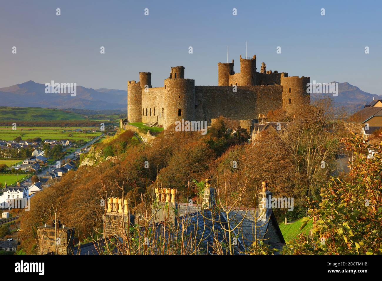 Harlech Castle in späten Abend Sonnenlicht und blauen Himmel mit Bergen in der Ferne, Snowdonia, North Wales, Großbritannien. Stockfoto