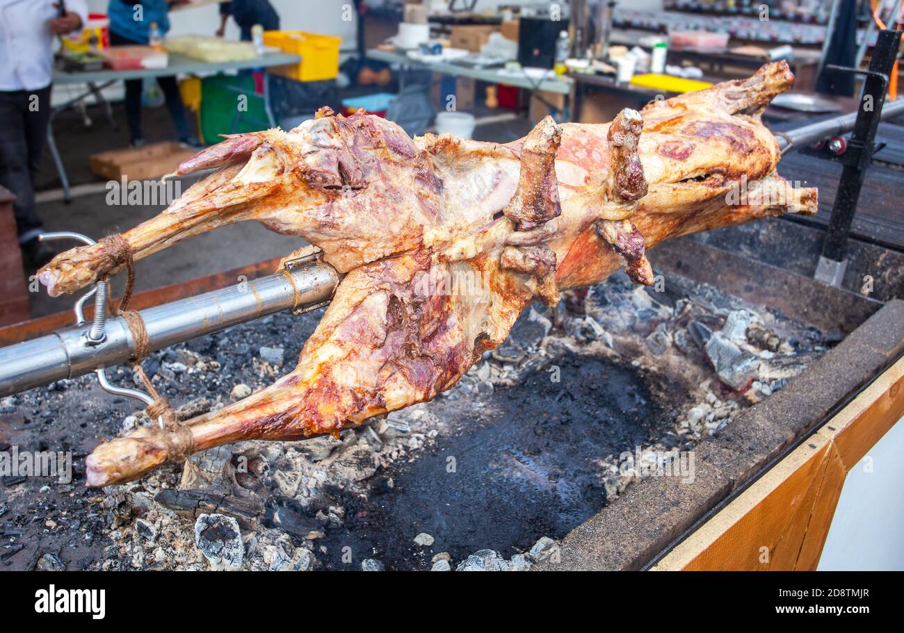 Kochen Lammkarkasse auf einem Spieß auf dem offenen Feuer des Grills auf dem Straßenmarkt geröstet. Traditionelle serbische Braten Lamm oder Schweinefleisch Grill Stockfoto