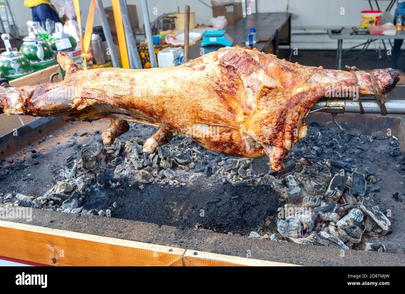Kochen Lammkarkasse auf einem Spieß auf dem offenen Feuer des Grills auf dem Straßenmarkt geröstet. Traditionelle serbische Braten Lamm oder Schweinefleisch Grill Stockfoto