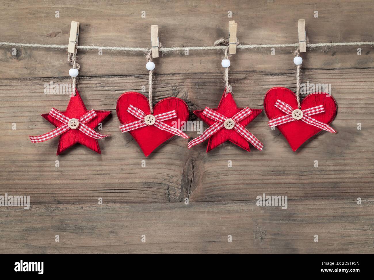 Weihnachtsschmuck Ornamente auf Schnur vor Holzhintergrund. Stockfoto