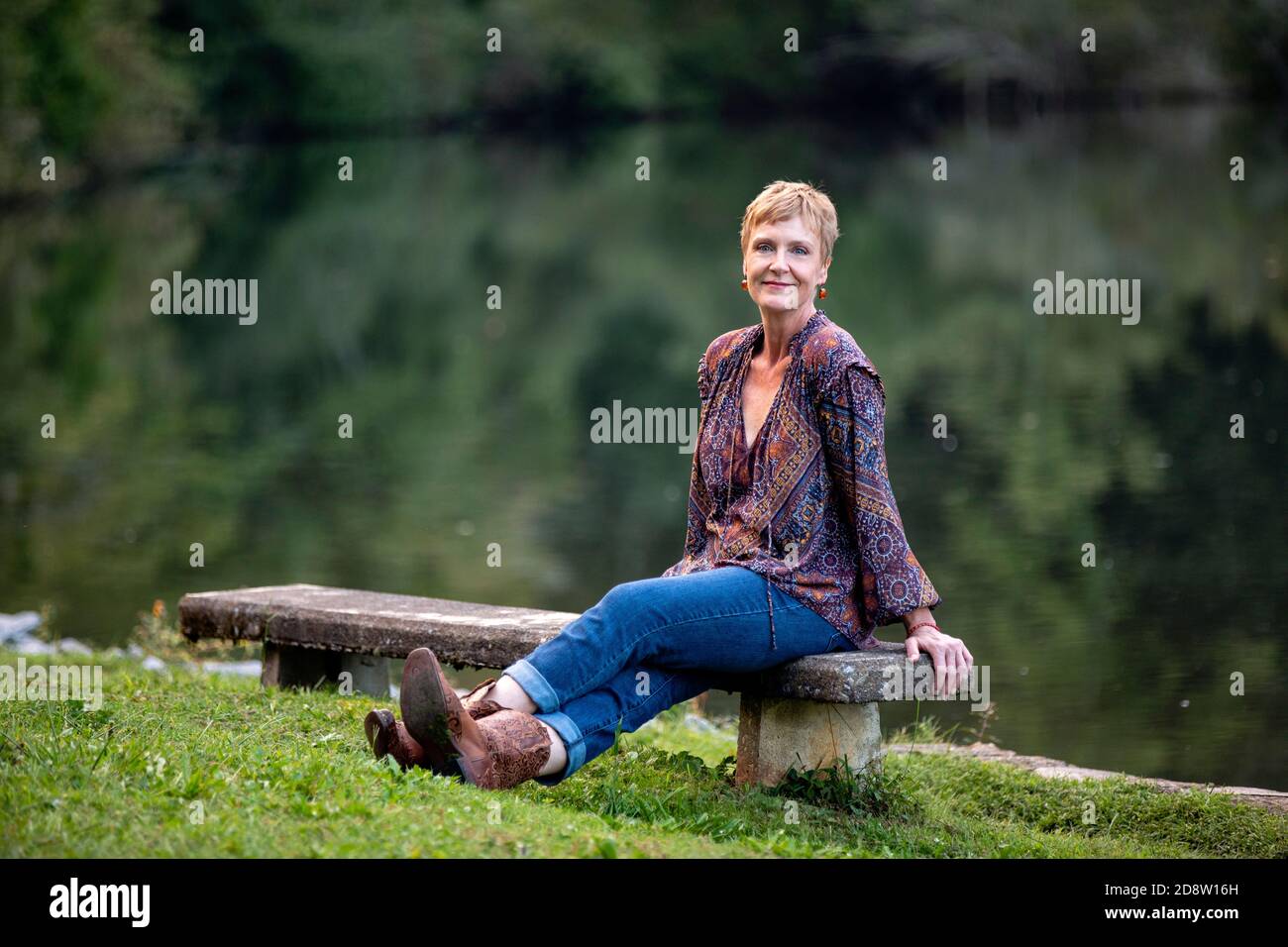 Frau, die am See sitzt und die Kamera anschaut - Brevard, North Carolina, USA Stockfoto