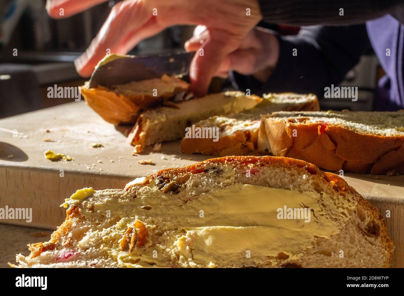 Barmbrack Laib mit Butter im Vordergrund. Eine weitere Schicht wird im Hintergrund geschnitten. Stockfoto