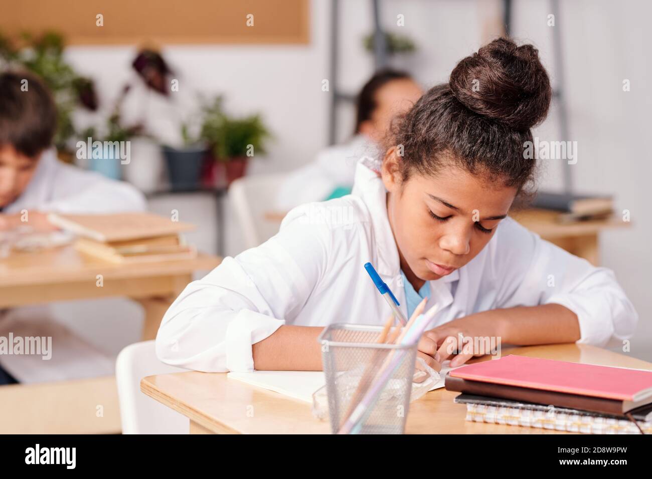 Zeitgenössische Mixed-Race-Schulmädchen in Whitecoat schriftlich chemische Formel Stockfoto