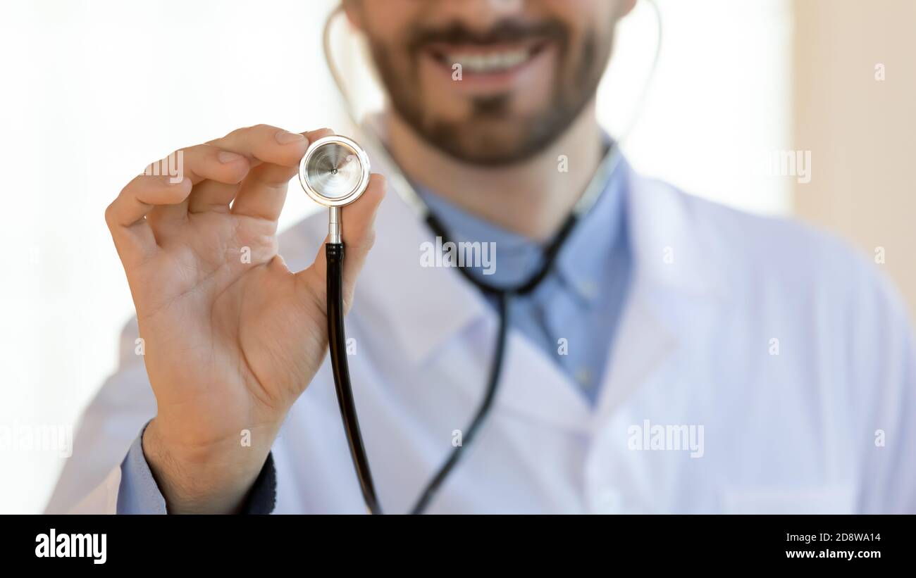 Lächelnder männlicher Kardiologe mit Stethoskop und schlägt dem Patienten vor, eine Untersuchung zu machen Stockfoto
