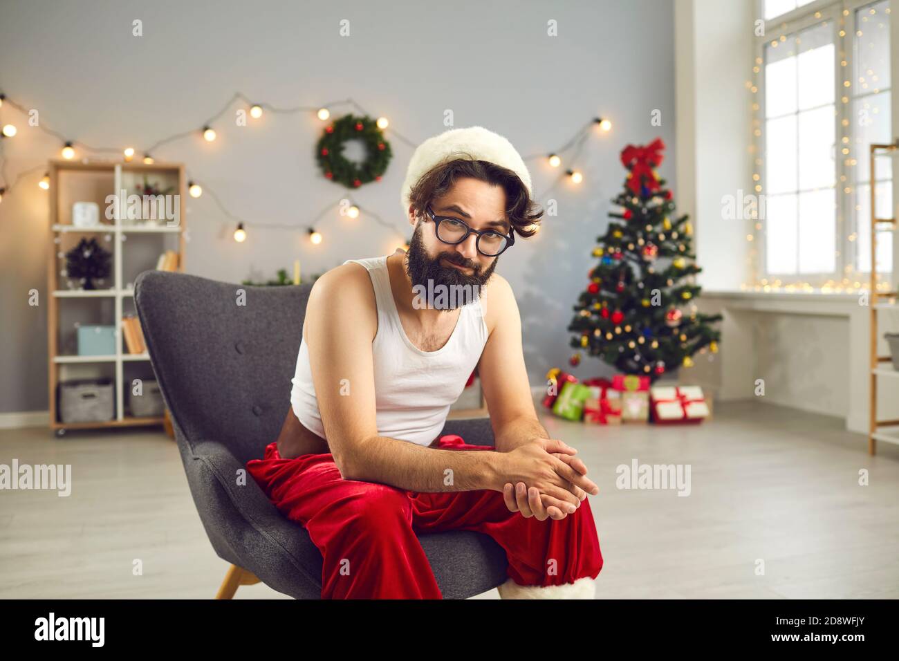 Positive lustige Weihnachtsmann in Hause festliche Kostüm sitzt in Sessel Stockfoto