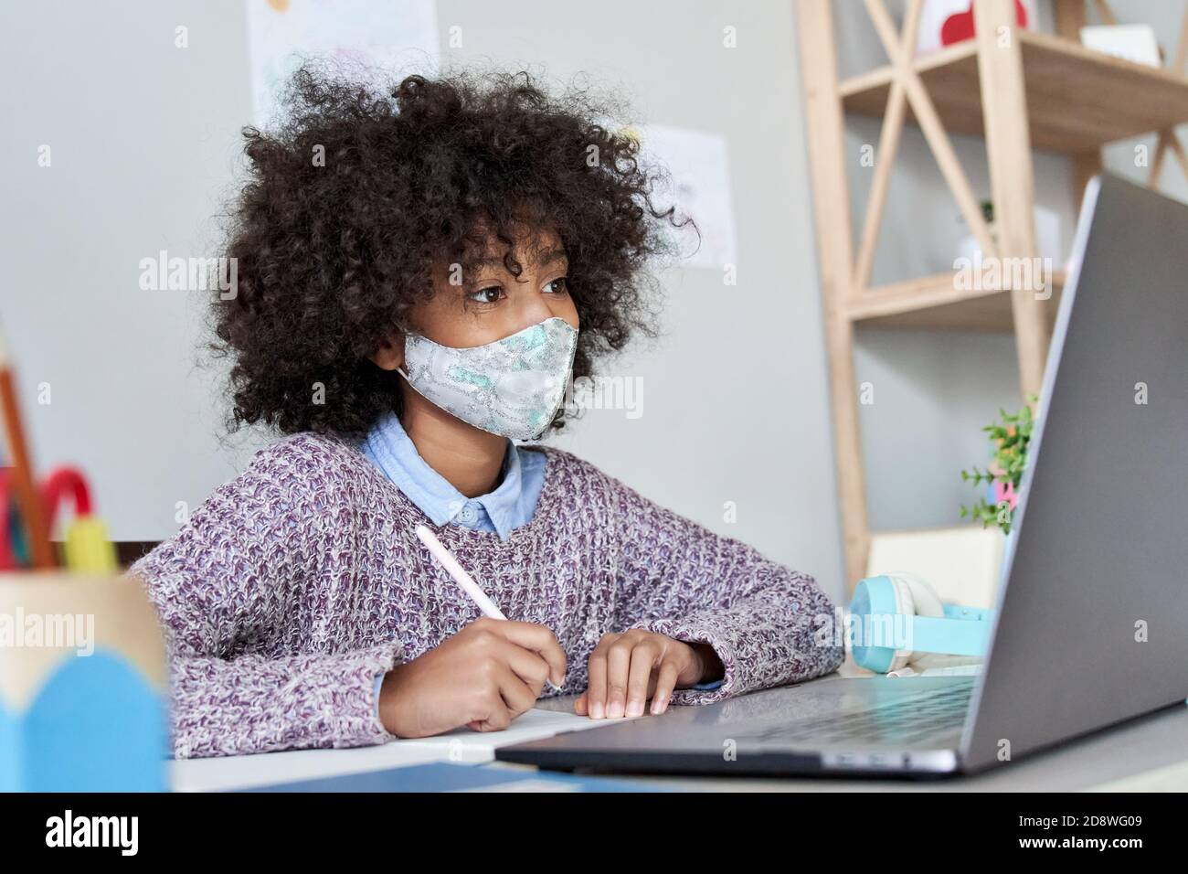 Afrikanische Schule Kind Mädchen trägt Gesichtsmaske beobachten Online-Klasse Distanz lernen. Stockfoto