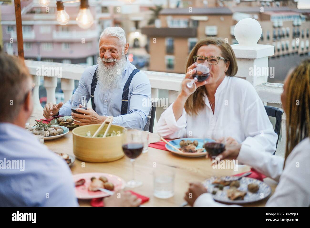 Ältere, multirassische Menschen, die beim Abendessen auf der Terrasse Spaß haben - glücklich Friends Eating at sunday Meal - Fokus auf Hipster Mann Gesicht Stockfoto