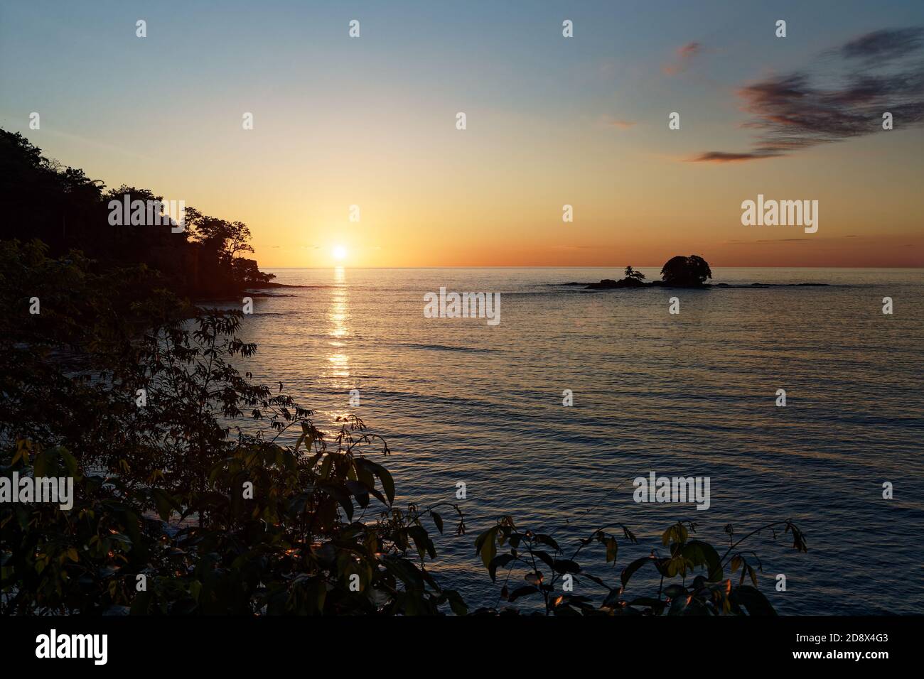 Pazifikküste von Costa Rica in Mittelamerika, Sonnenuntergang am Abend mit Palmen, Meer und Wolken auf dem roten Himmel. Stockfoto