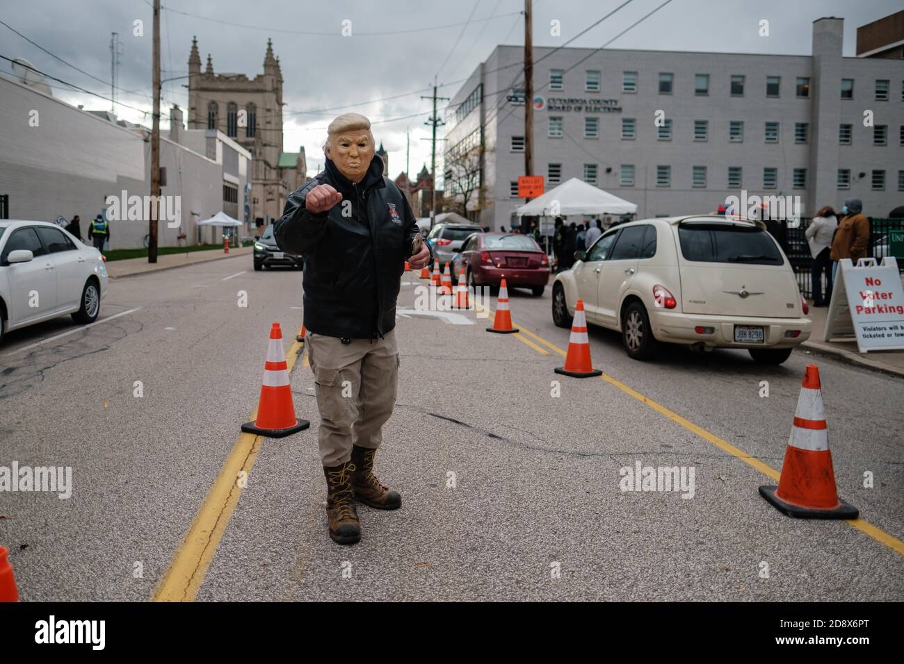 Cleveland, Ohio, USA. November 2020. Ein Mann, der eine Donald Trump Halloween Maske trägt, pumpt seine Faust, während er mitten auf der Straße in der Nähe des Cuyahoga County Board of Elections, Sonntag, 1. November 2020 in Cleveland, Ohio, unterwegs ist. Die Wähler kamen über eine Stunde vor der Eröffnung um 13 Uhr an und stimmten bis 17 Uhr, nur 48 Stunden vor dem Wahltag. Quelle: Andrew Dolph/ZUMA Wire/Alamy Live News Stockfoto