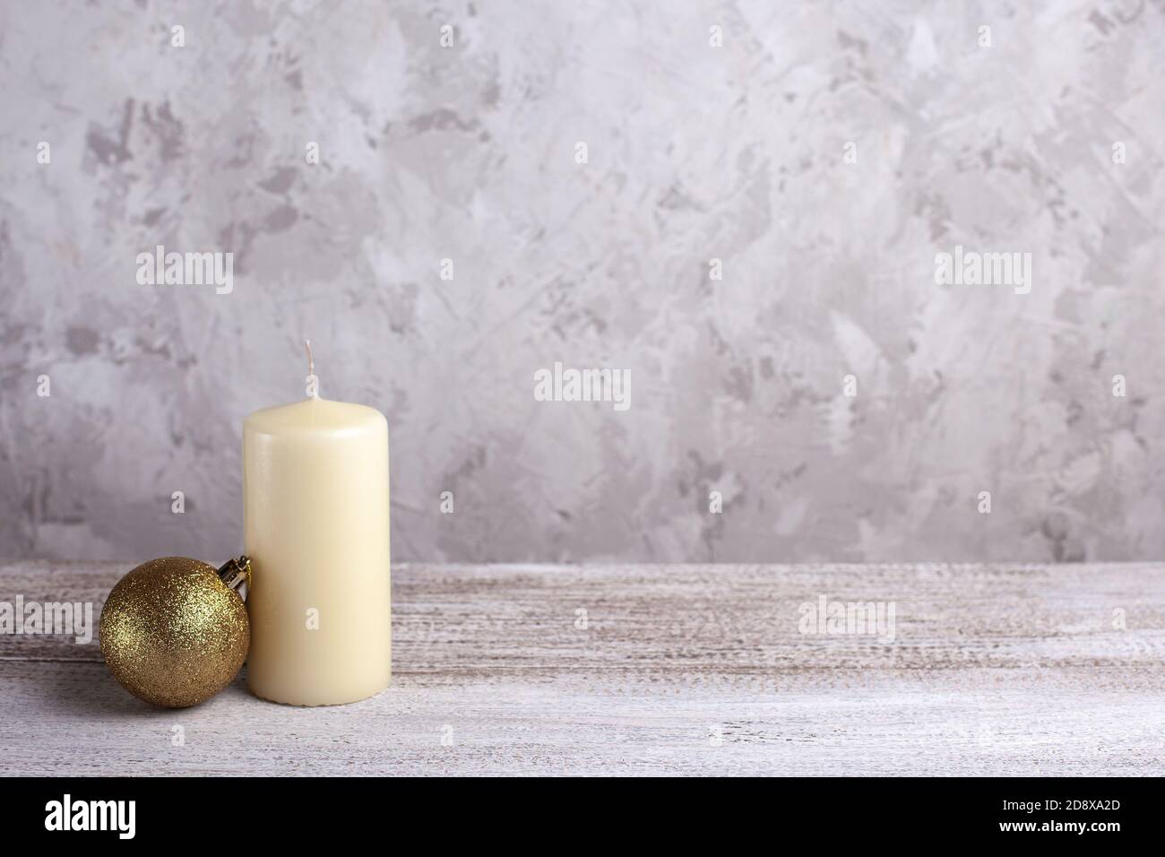 Nachbau der Vanillekerze, ein goldener Weihnachtsball auf einem Holztisch Stockfoto