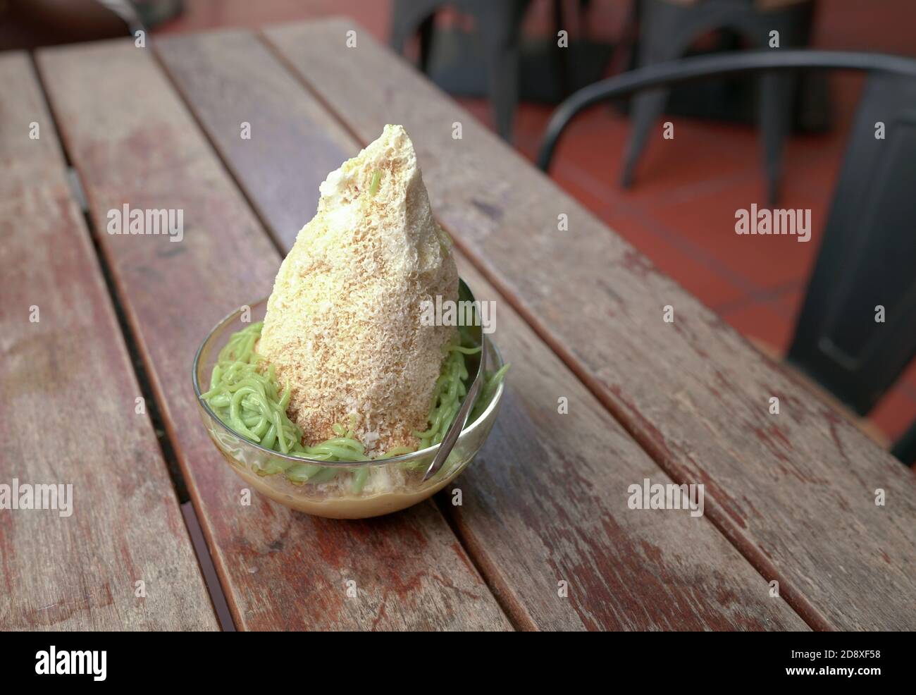 Cendol, süß rasierte Eis mit grünem Reismehl Gelee in einer Schüssel serviert, auf einem Holztisch Stockfoto