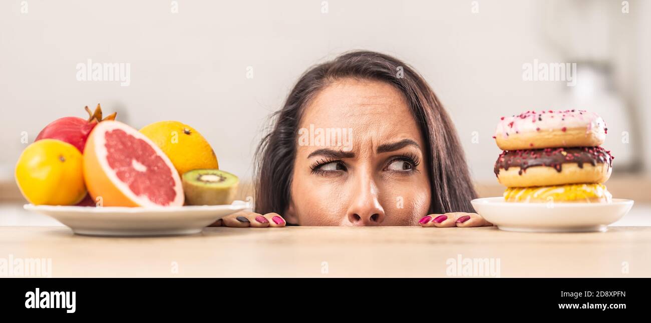 Verdächtiger Ausdruck über einem Teller mit Donuts neben einem Obstteller. Stockfoto