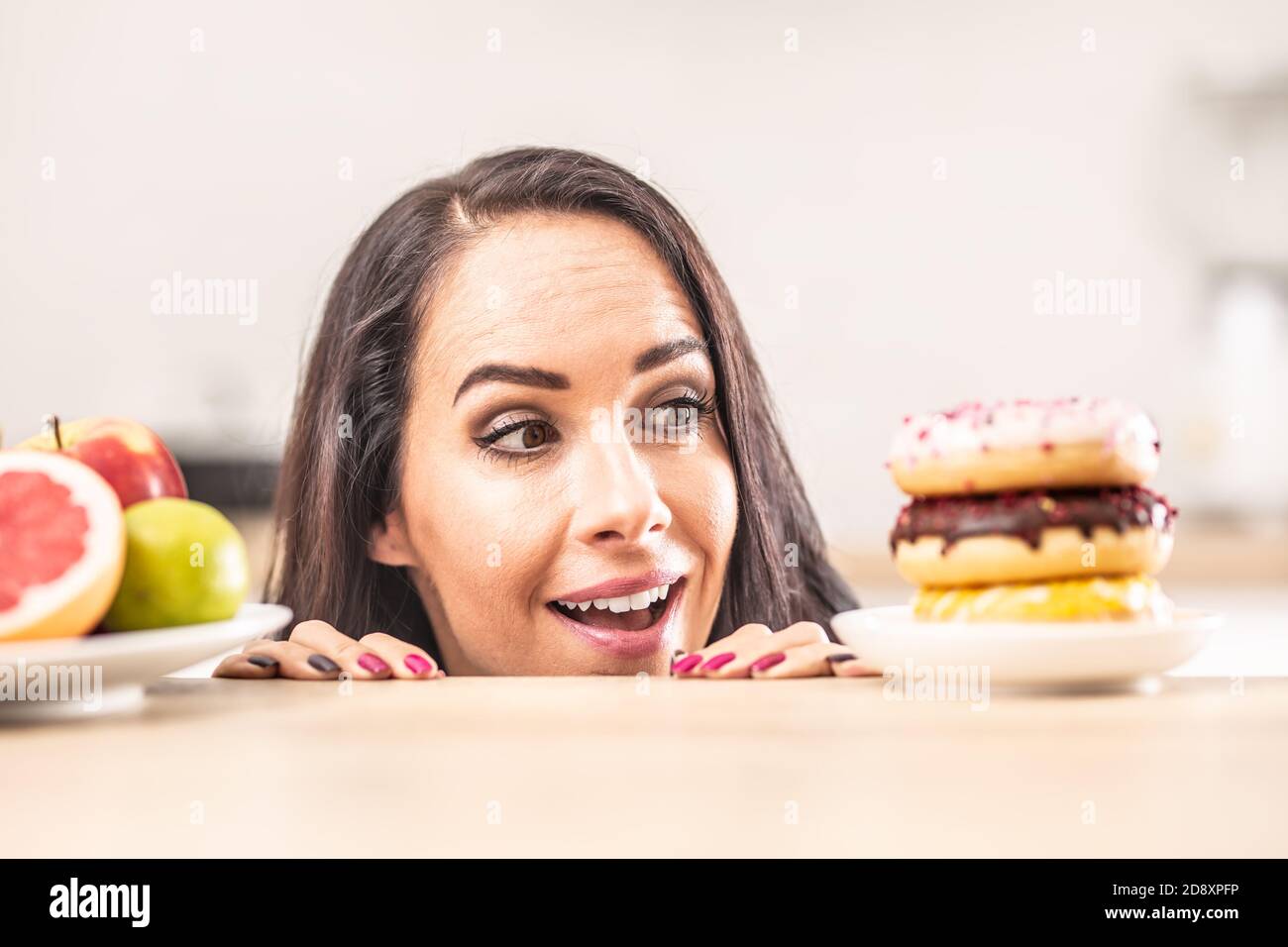 Mädchen bevorzugt plateful von Donuts anstelle eines Tellers mit frischen Früchten. Stockfoto