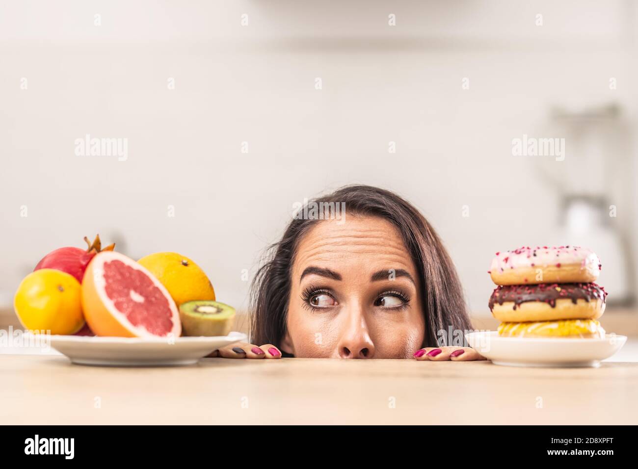 Frisches Obst über ungesunde Donuts Präferenz von einer Frau in der Küche. Stockfoto