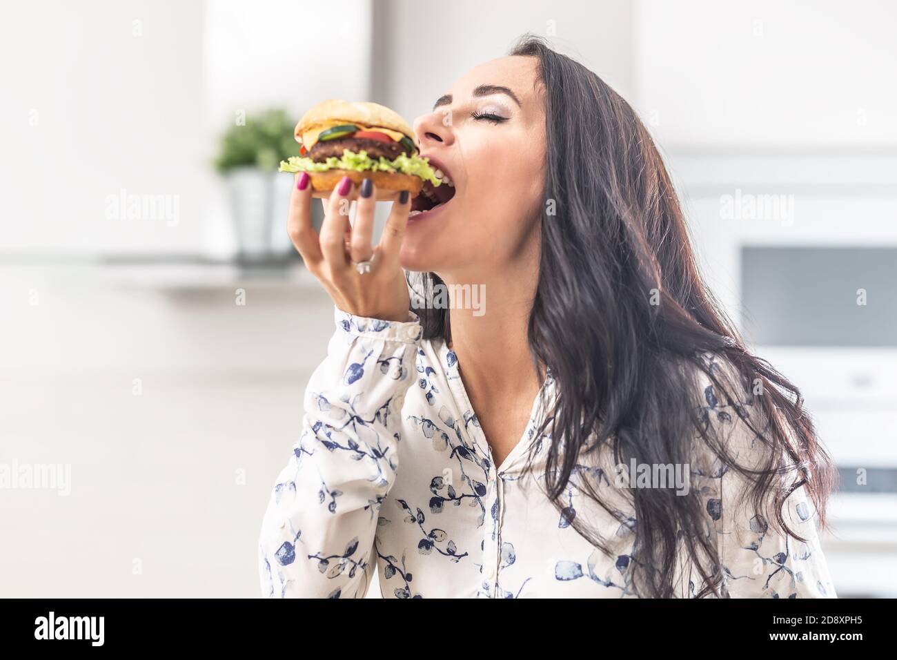 Genießen Sie einen Biss eines Hamburgers von einer Frau. Stockfoto