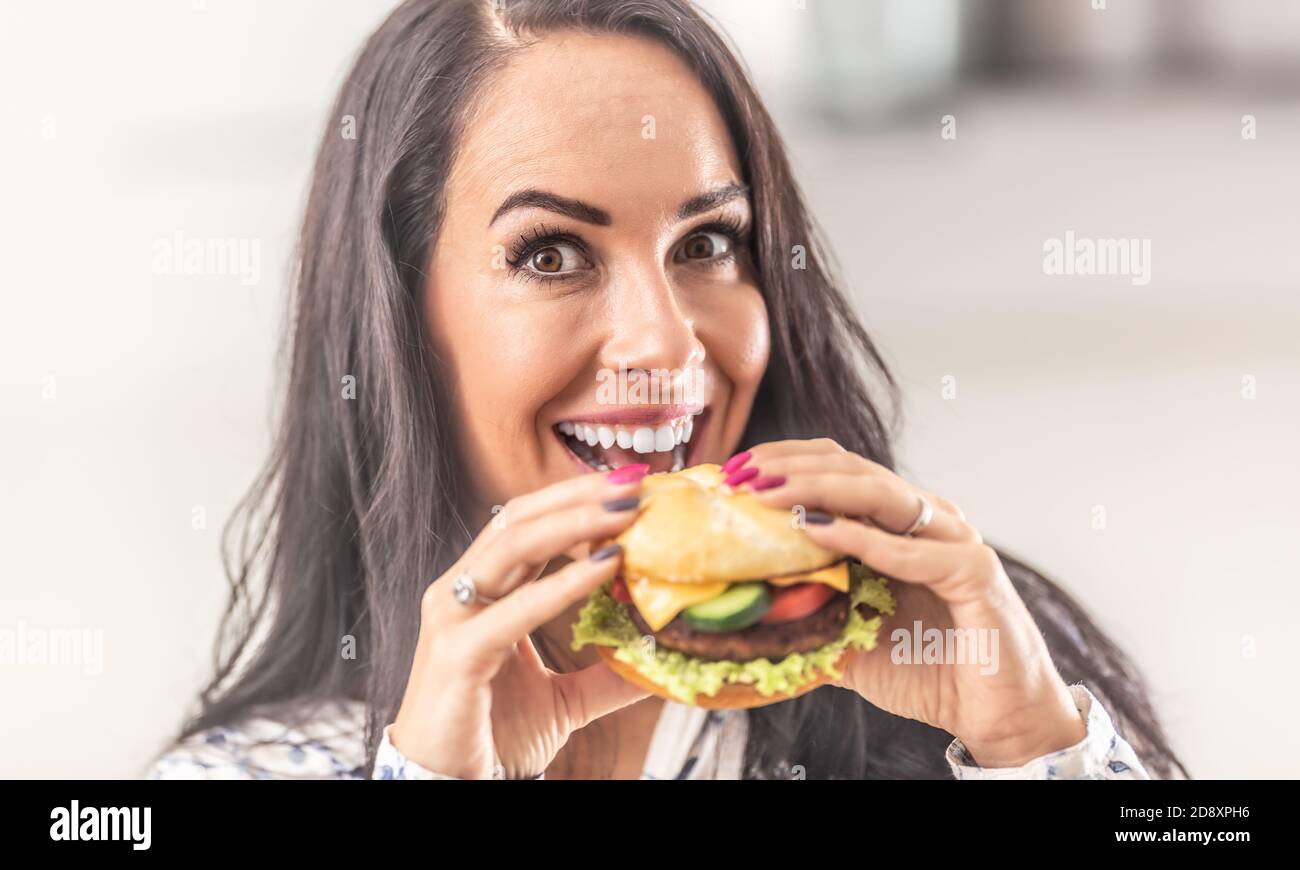 Schöne Frau hält einen Burger in den Händen mit einem Lächeln. Stockfoto